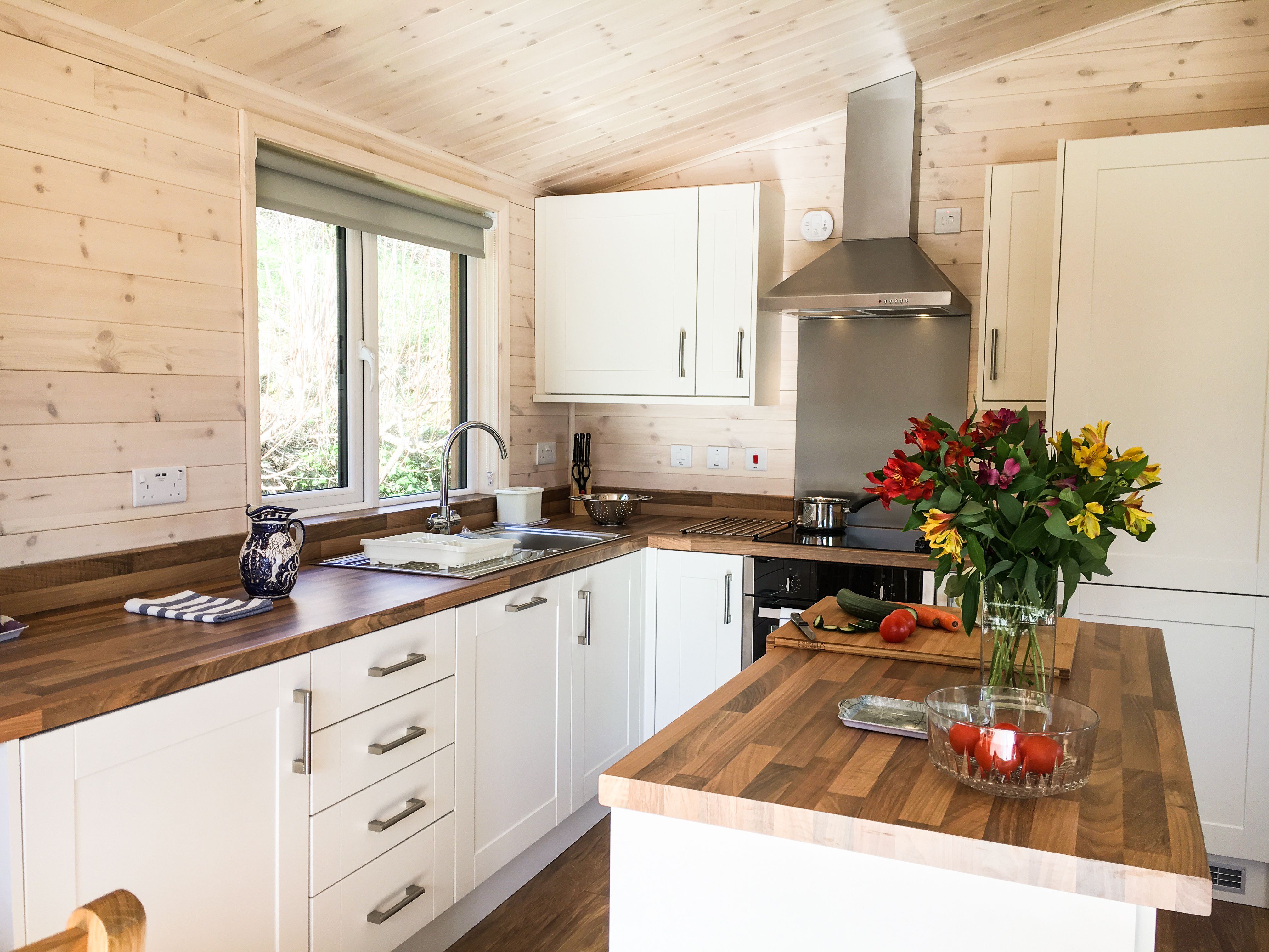Modern kitchen with wooden countertops, white cabinets, and a vase of flowers