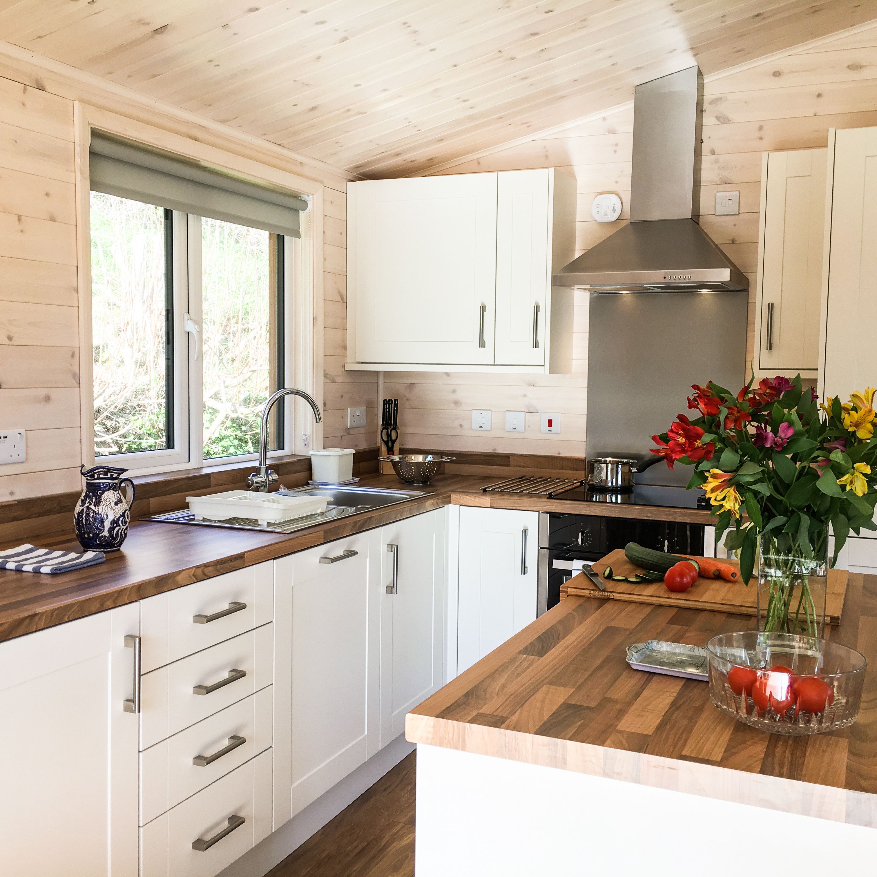 Modern kitchen with wooden countertops, white cabinets, and a vase of flowers