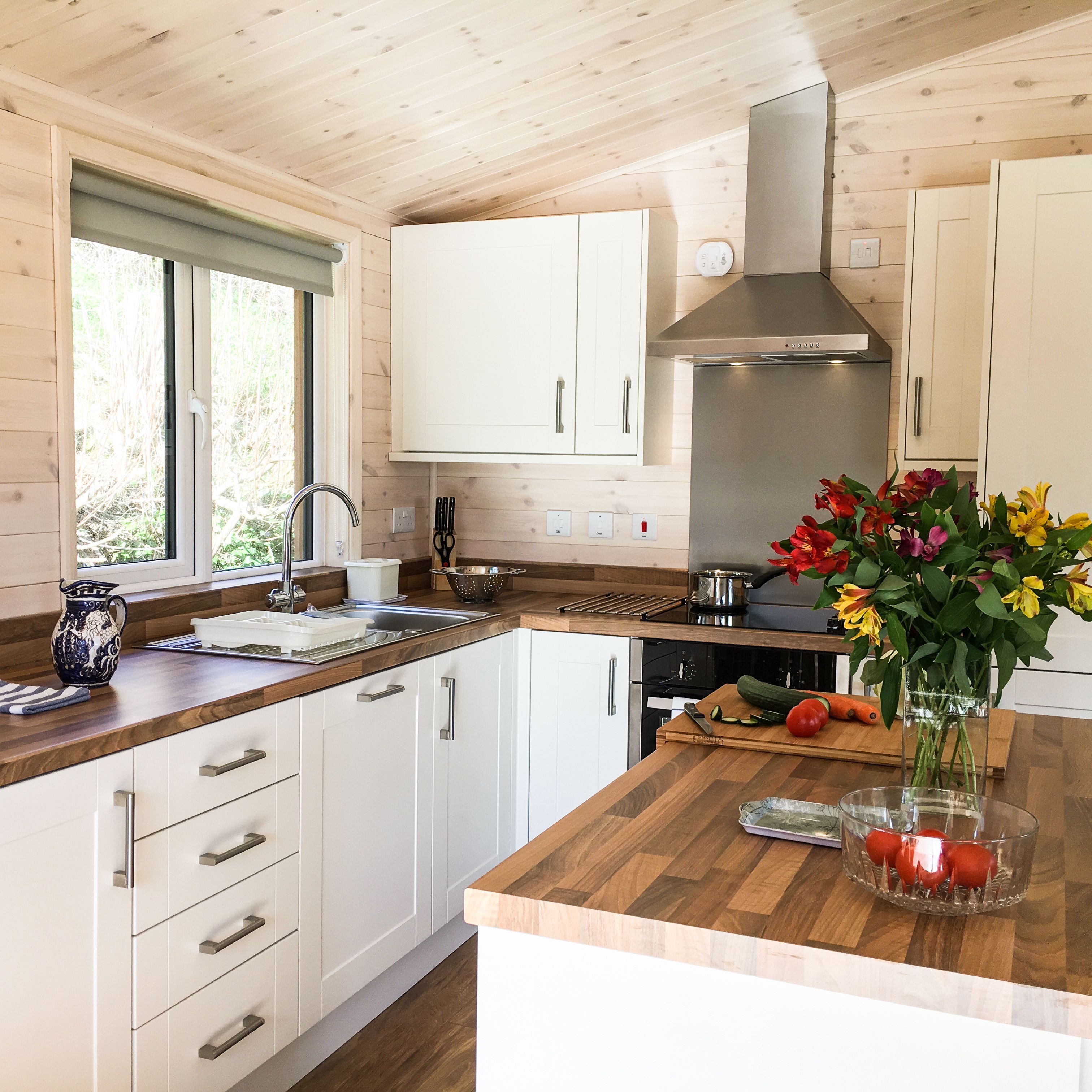Modern kitchen with wooden countertops, white cabinets, and a vase of flowers