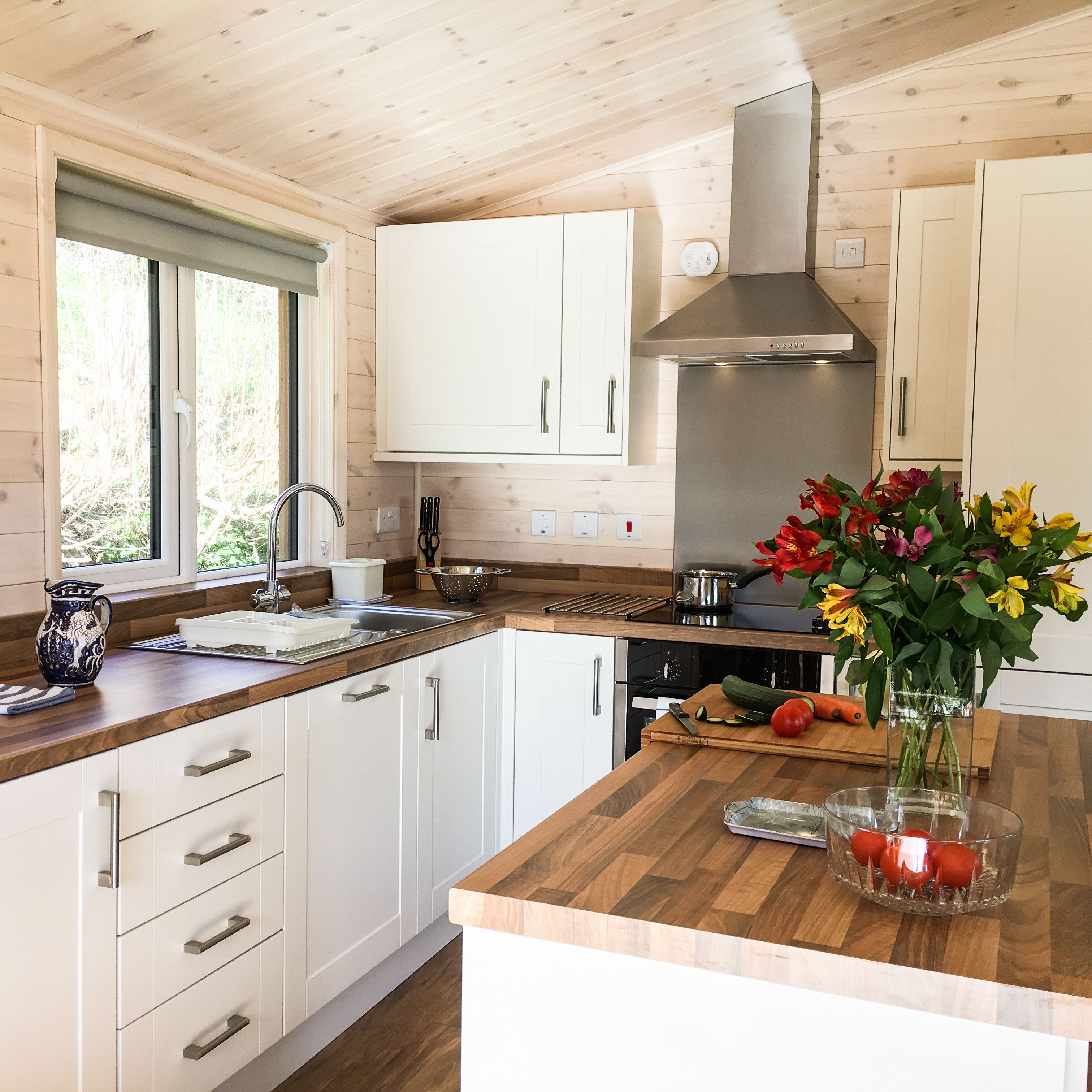 Modern kitchen with wooden countertops, white cabinets, and a vase of flowers