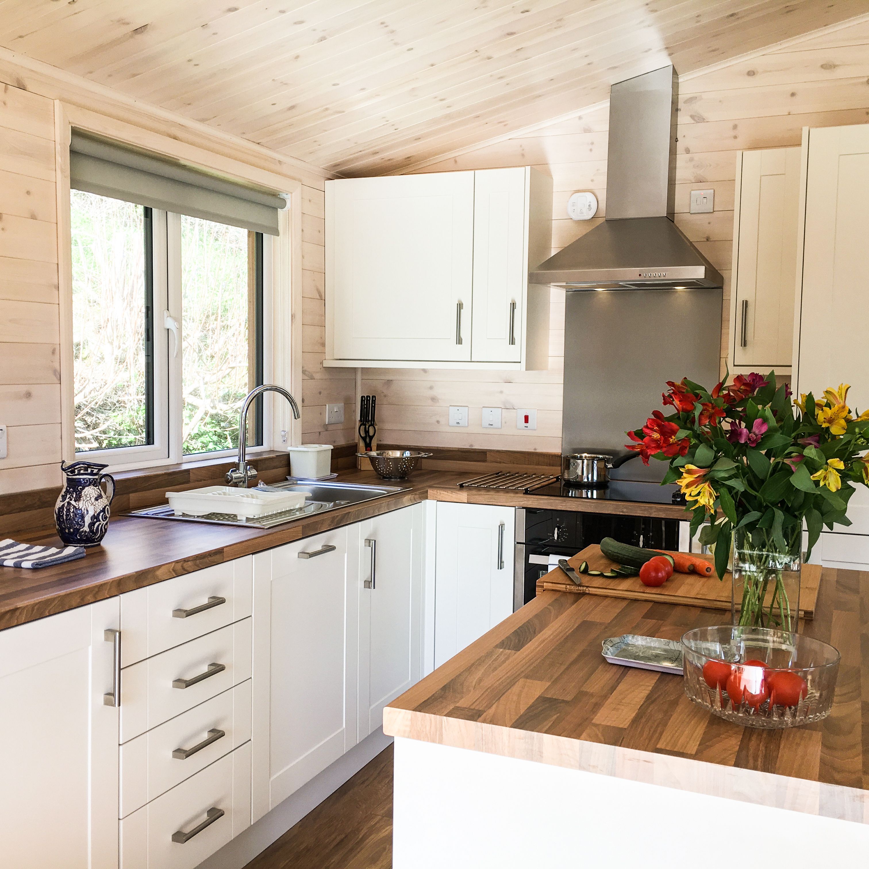 Modern kitchen with wooden countertops, white cabinets, and a vase of flowers