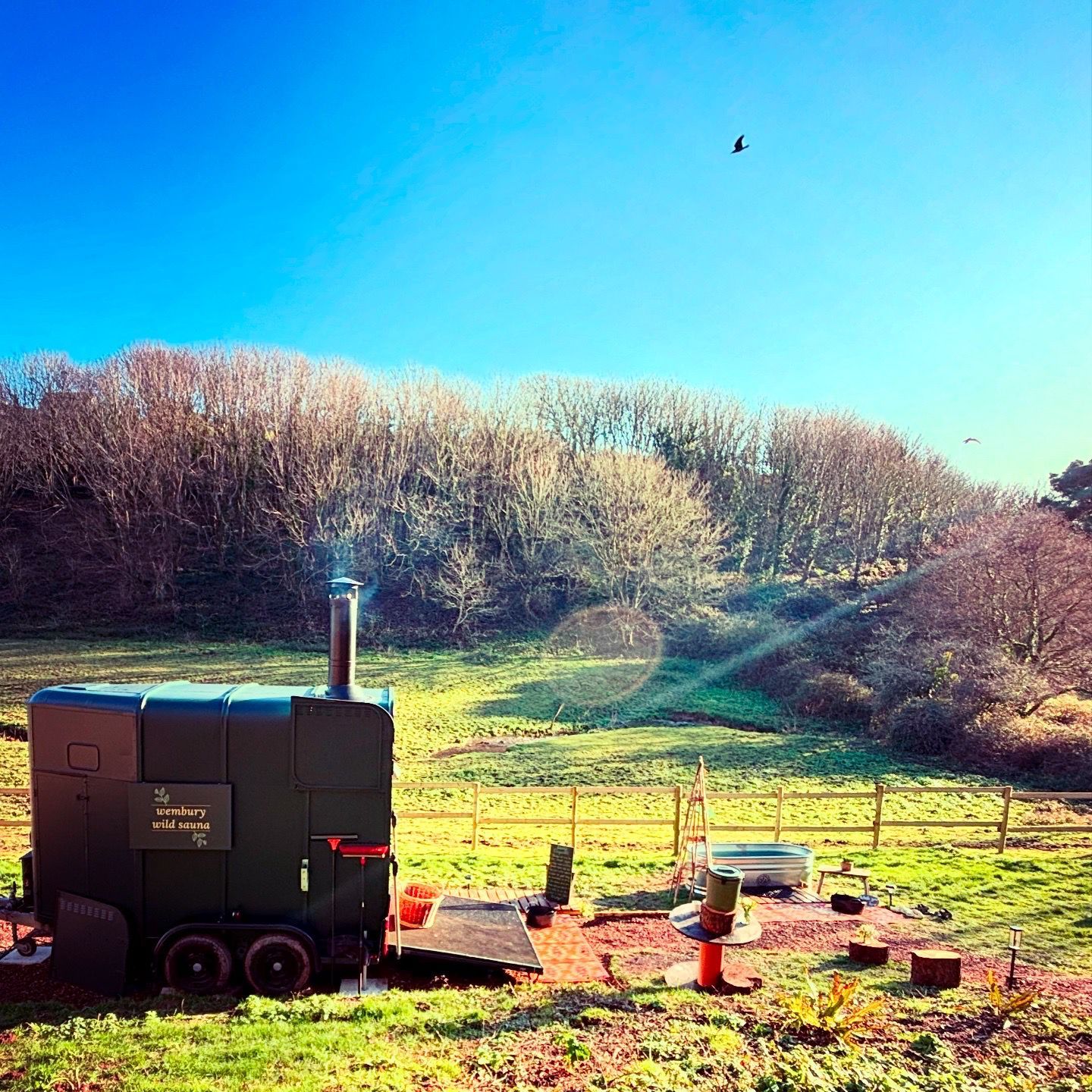 Mobile wood-fired sauna trailer in a sunny countryside field