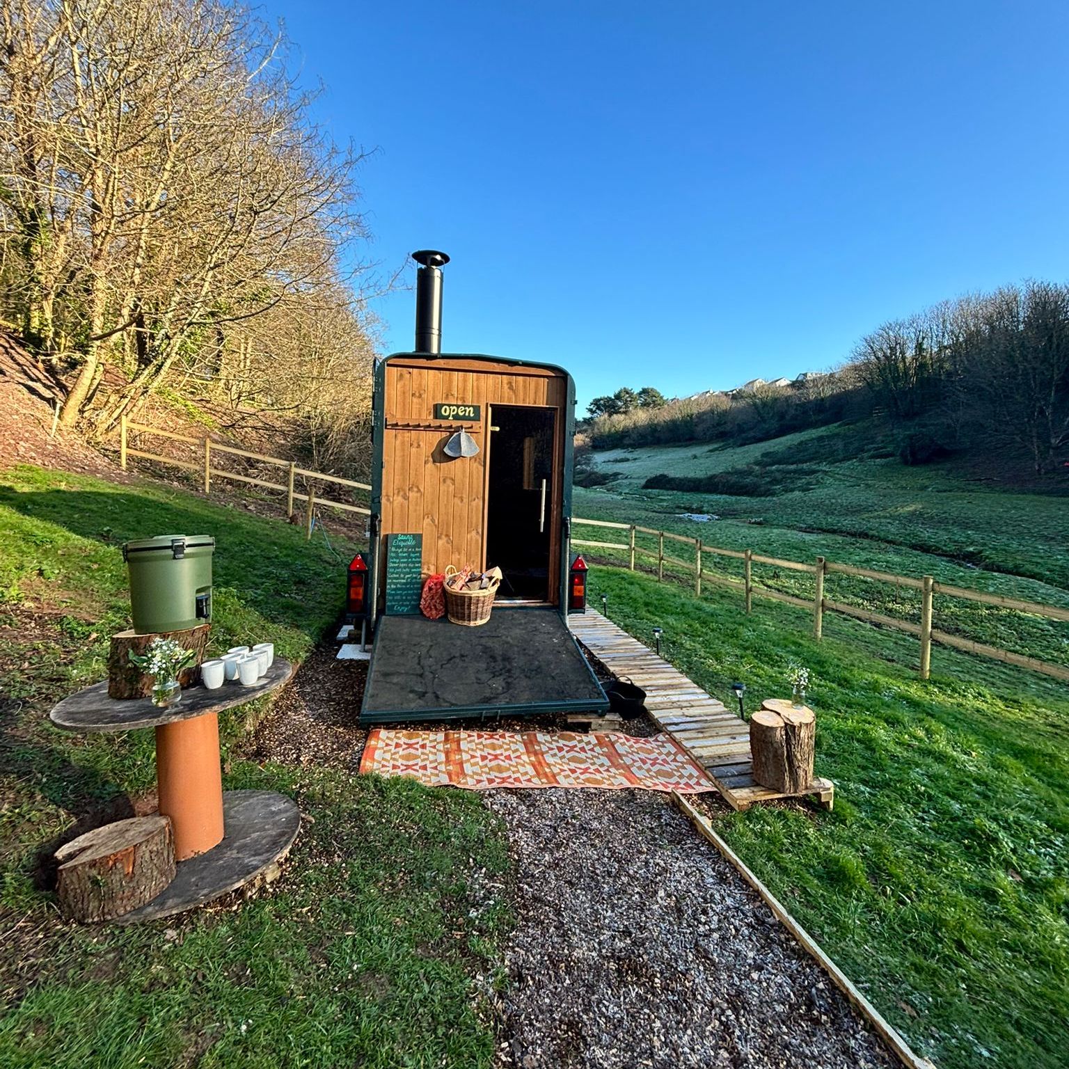Wooden shepherd’s hut with open door in a frosty hillside field under a clear blue sky