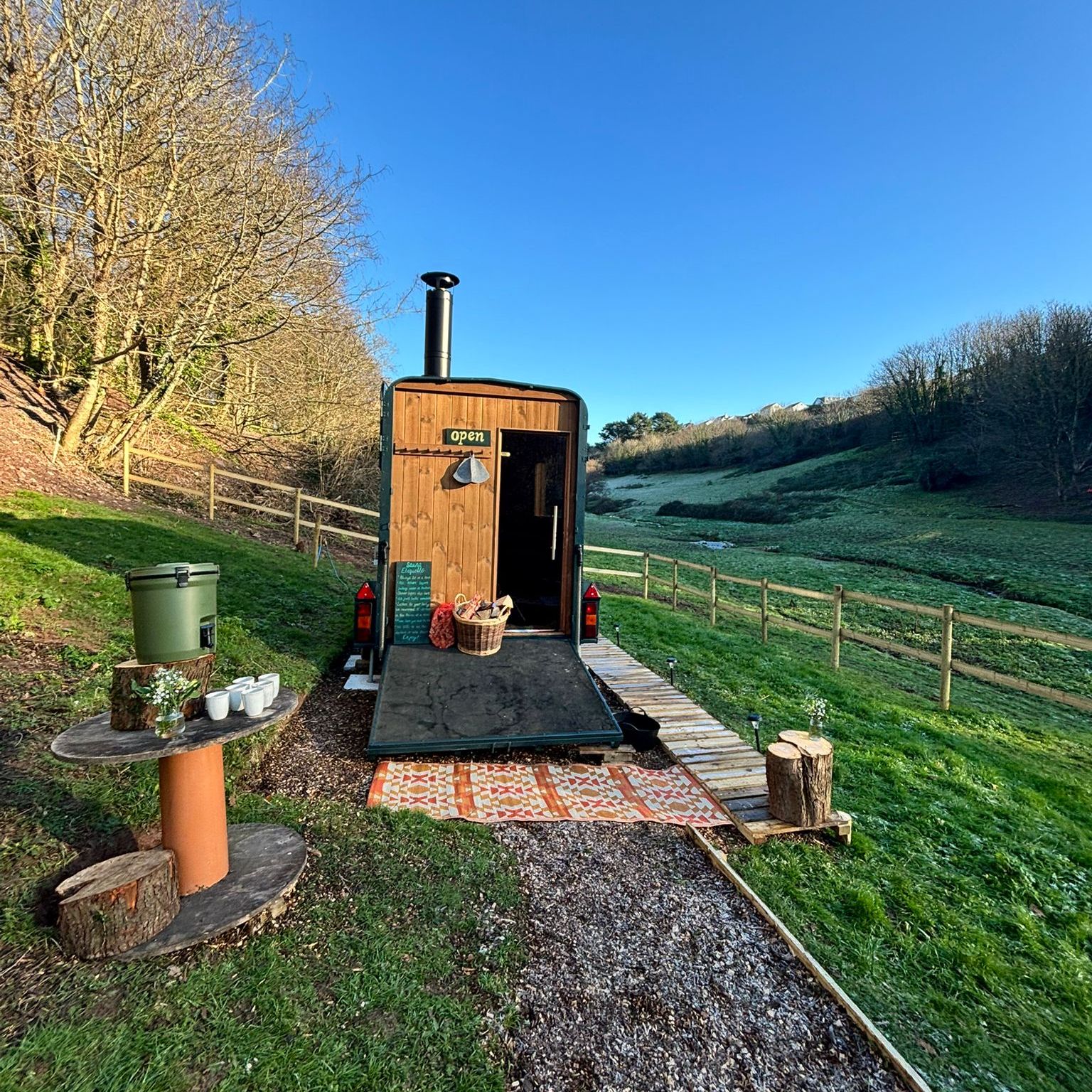 Wooden shepherd’s hut with open door in a frosty hillside field under a clear blue sky
