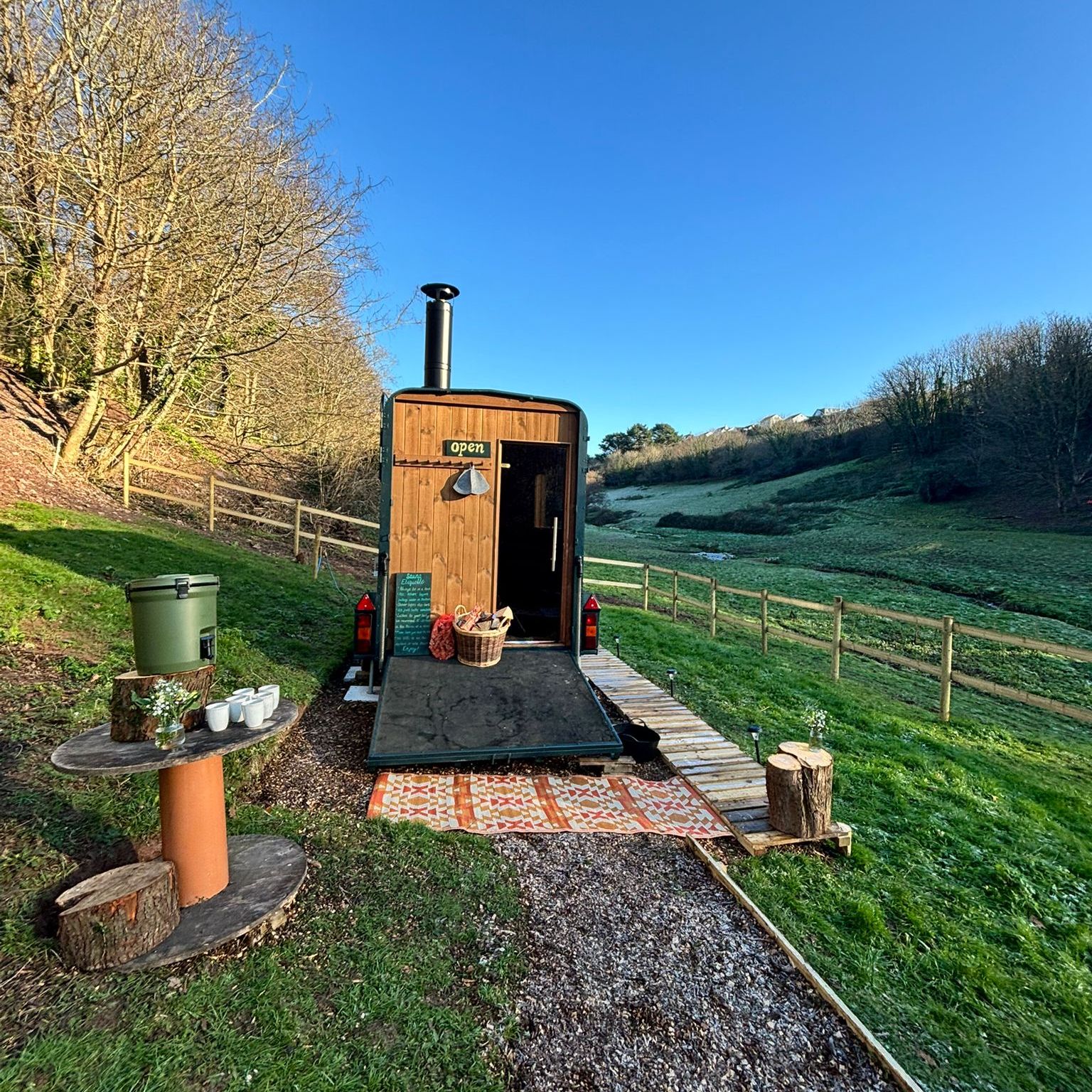 Wooden shepherd’s hut with open door in a frosty hillside field under a clear blue sky