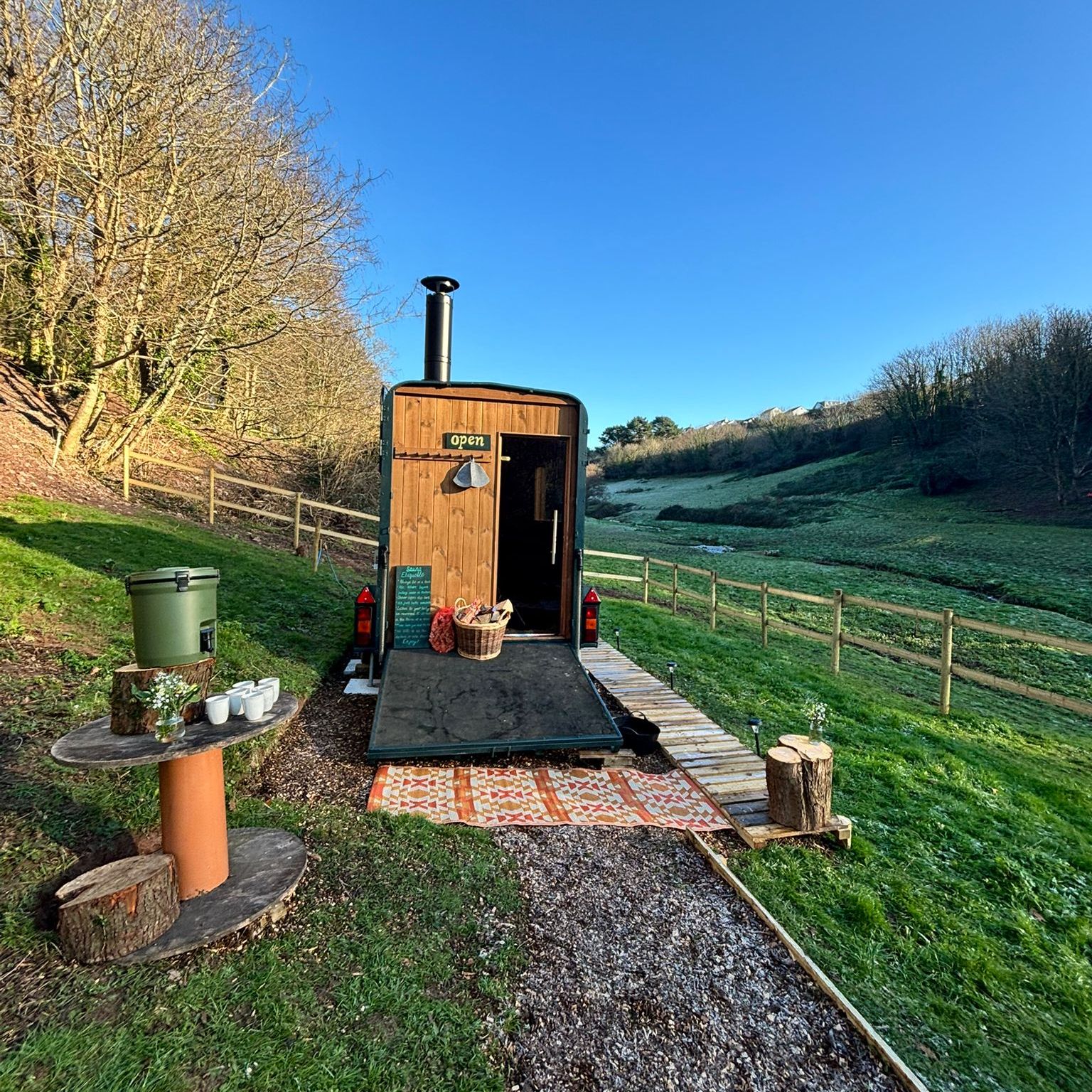 Wooden shepherd’s hut with open door in a frosty hillside field under a clear blue sky