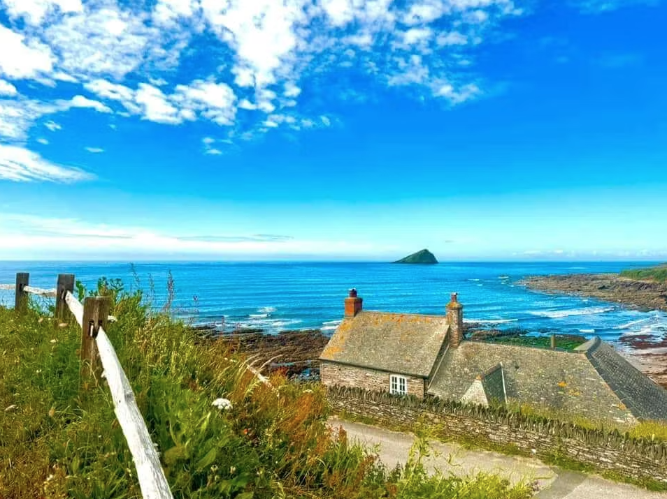 Coastal cottage overlooking the sea under a bright blue sky