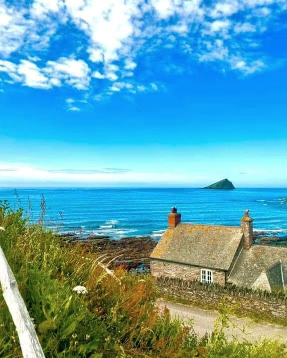 Coastal cottage overlooking the sea under a bright blue sky