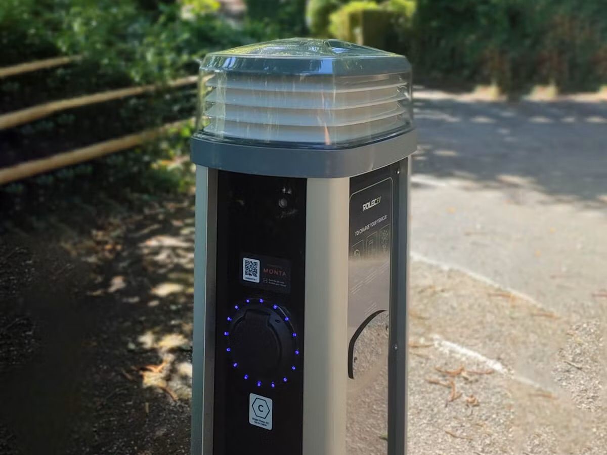 Electric vehicle charging point by a tree-lined path in a park