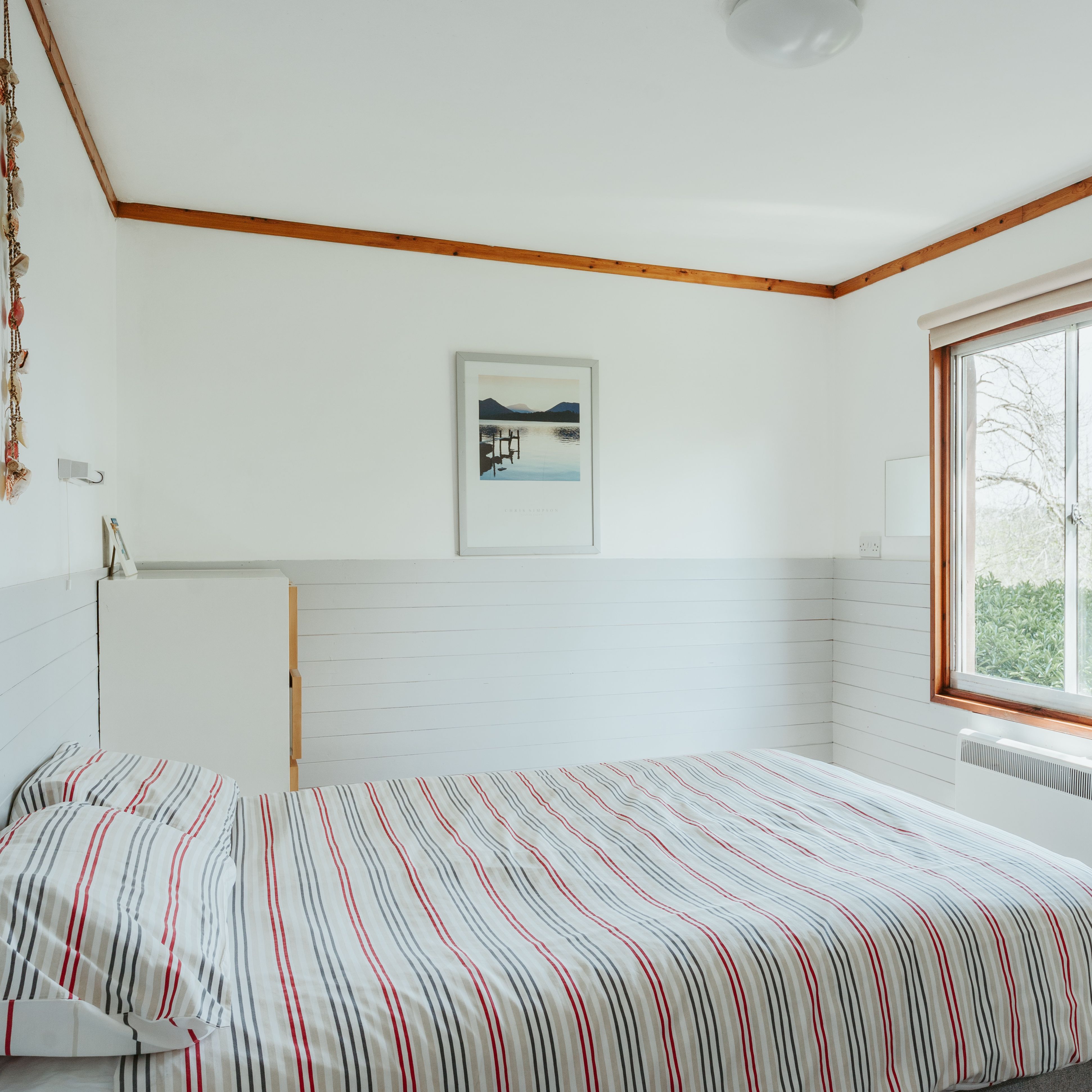 Bright bedroom with striped bedding and a large window