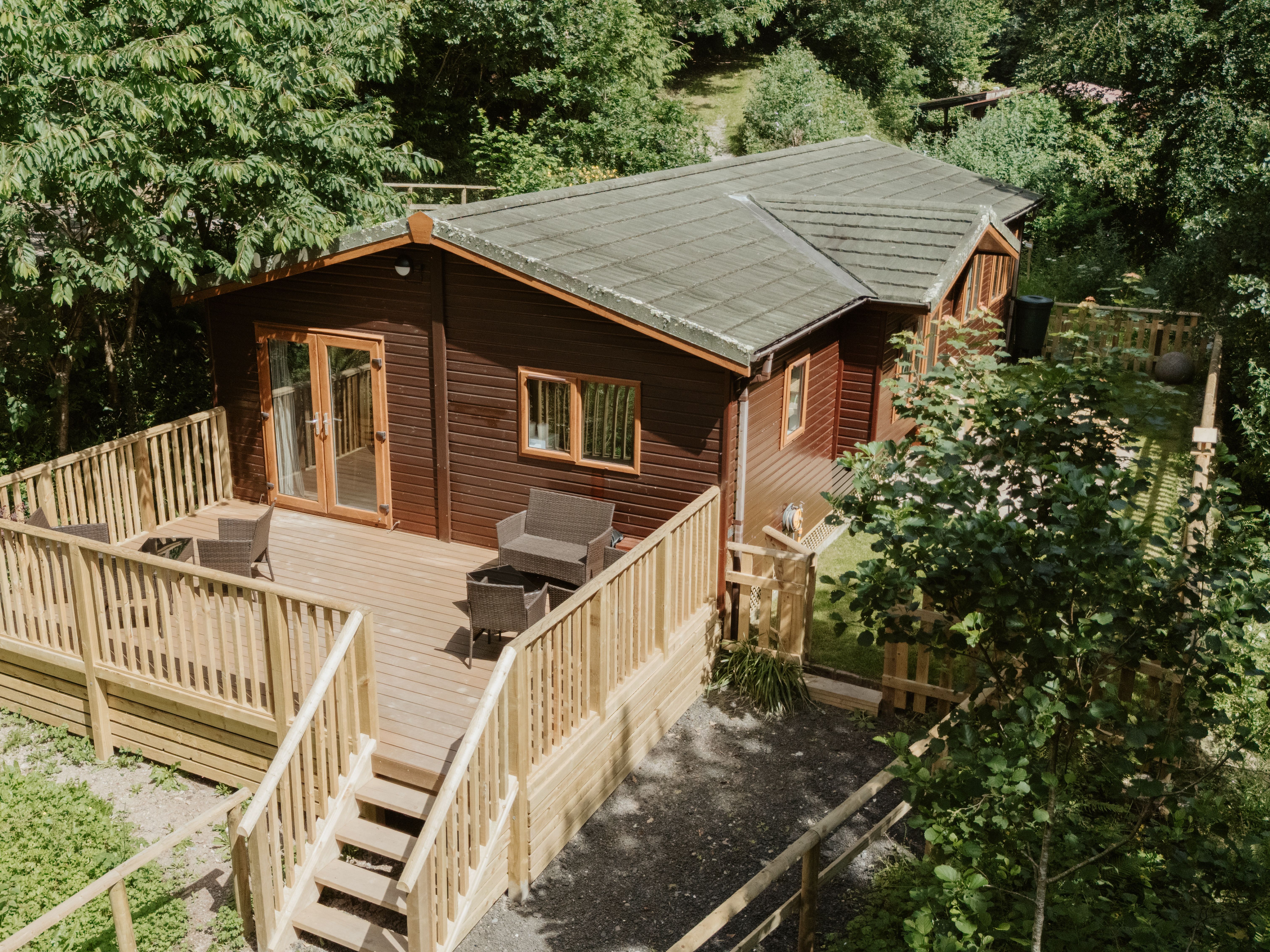 Woodland lodge cabin with large wooden deck and outdoor seating among trees