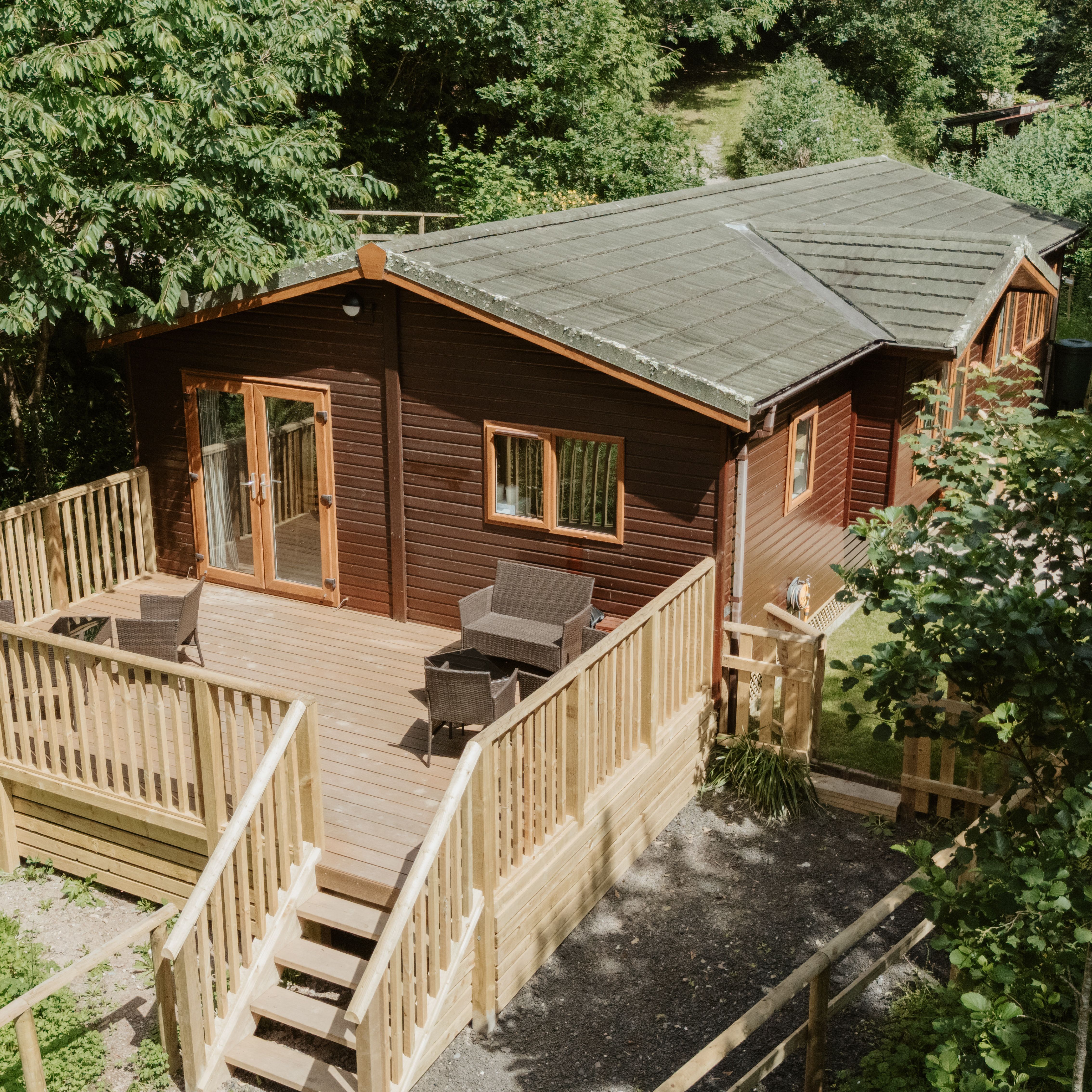 Woodland lodge cabin with large wooden deck and outdoor seating among trees