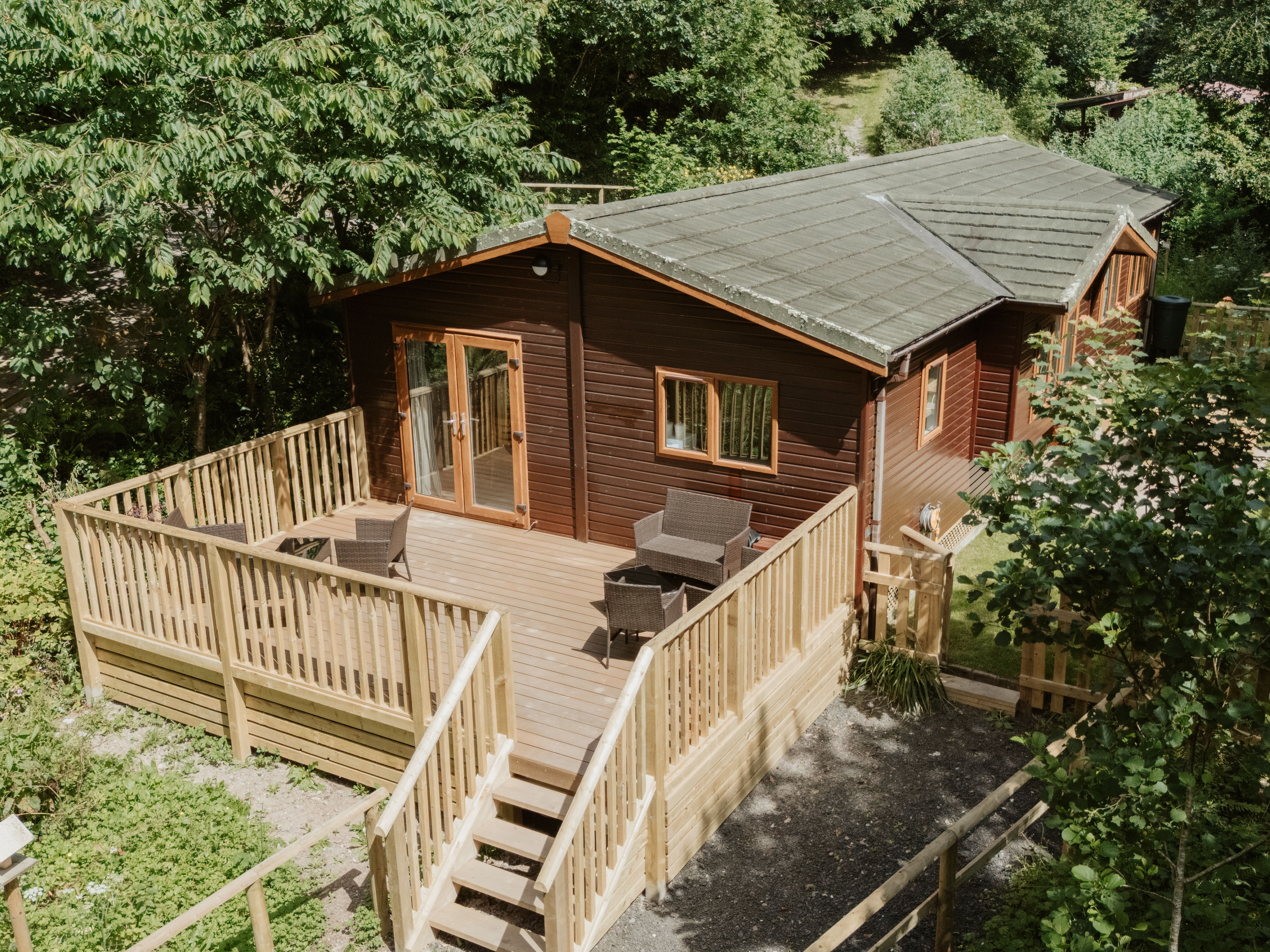 Woodland lodge cabin with large wooden deck and outdoor seating among trees