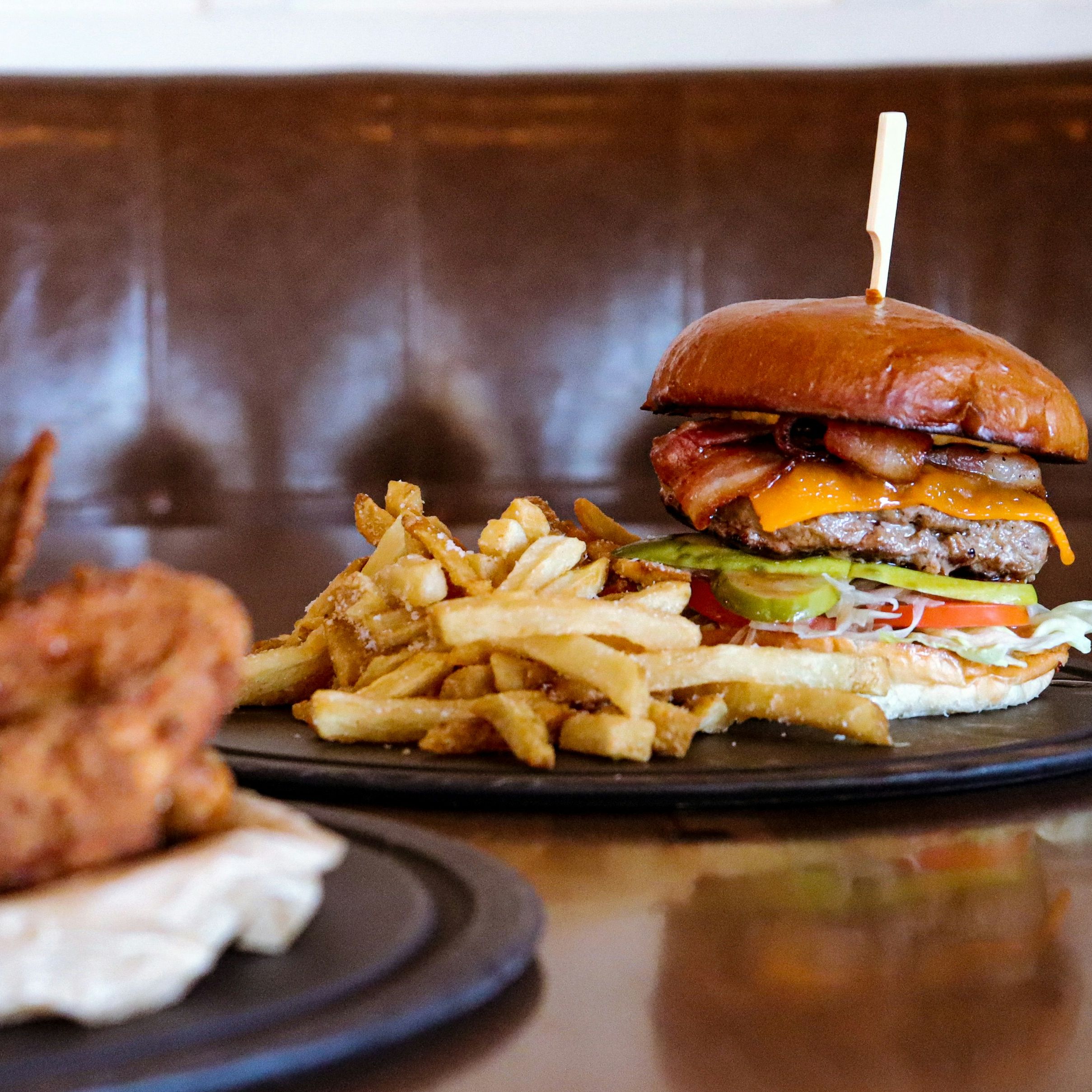 Burger with fries, chicken wings, and beer on a table