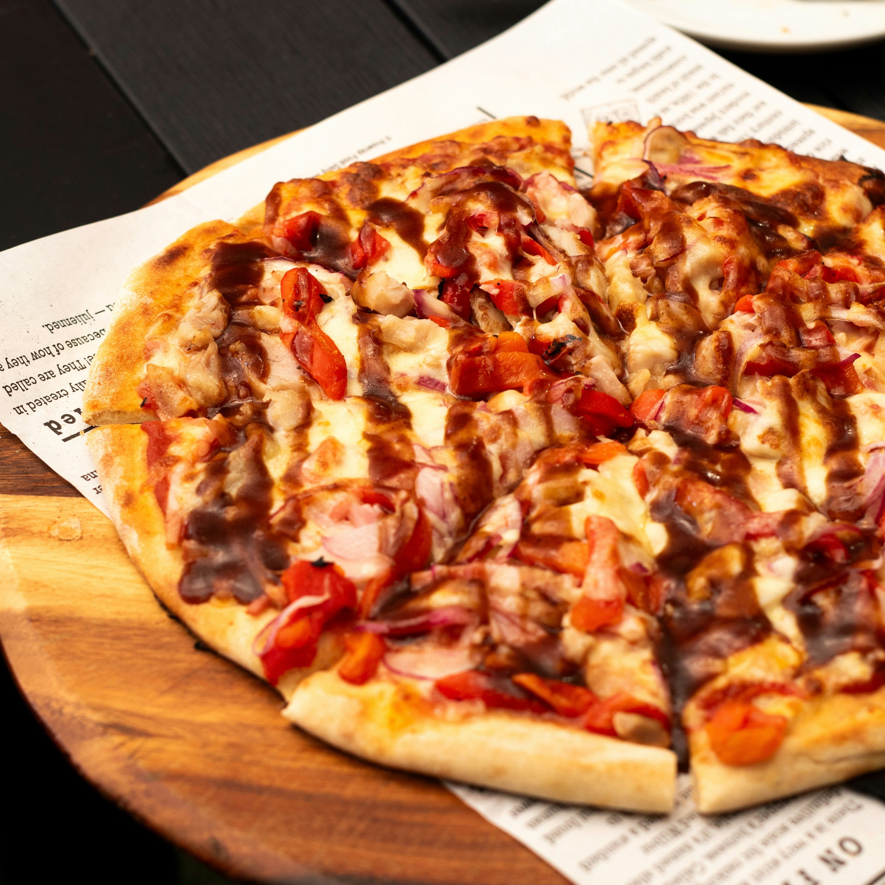 Barbecue chicken pizza with onions and peppers on a wooden serving board
