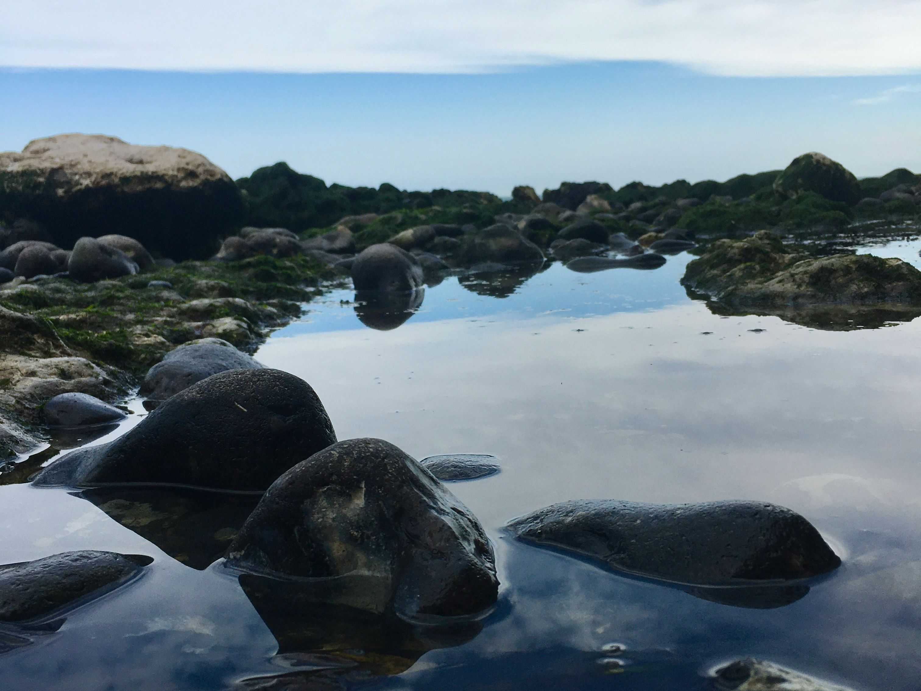 Close-up view of rocks and water reflecting the sky at a rocky shoreline