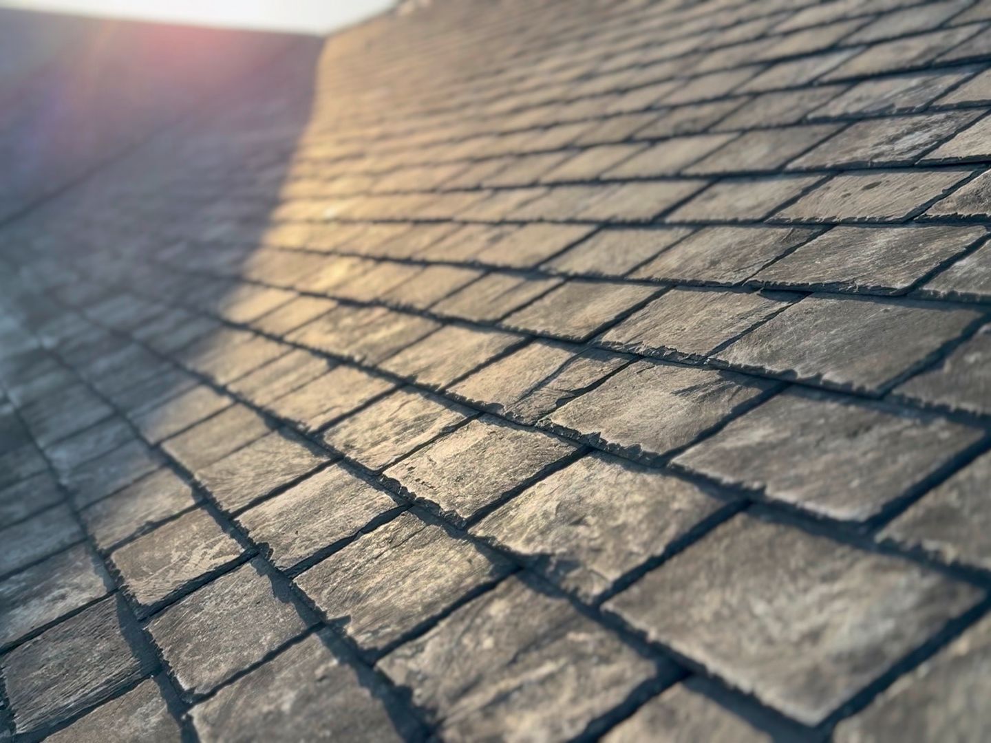 Close-up view of a slate tile roof with sunlight hitting the surface.