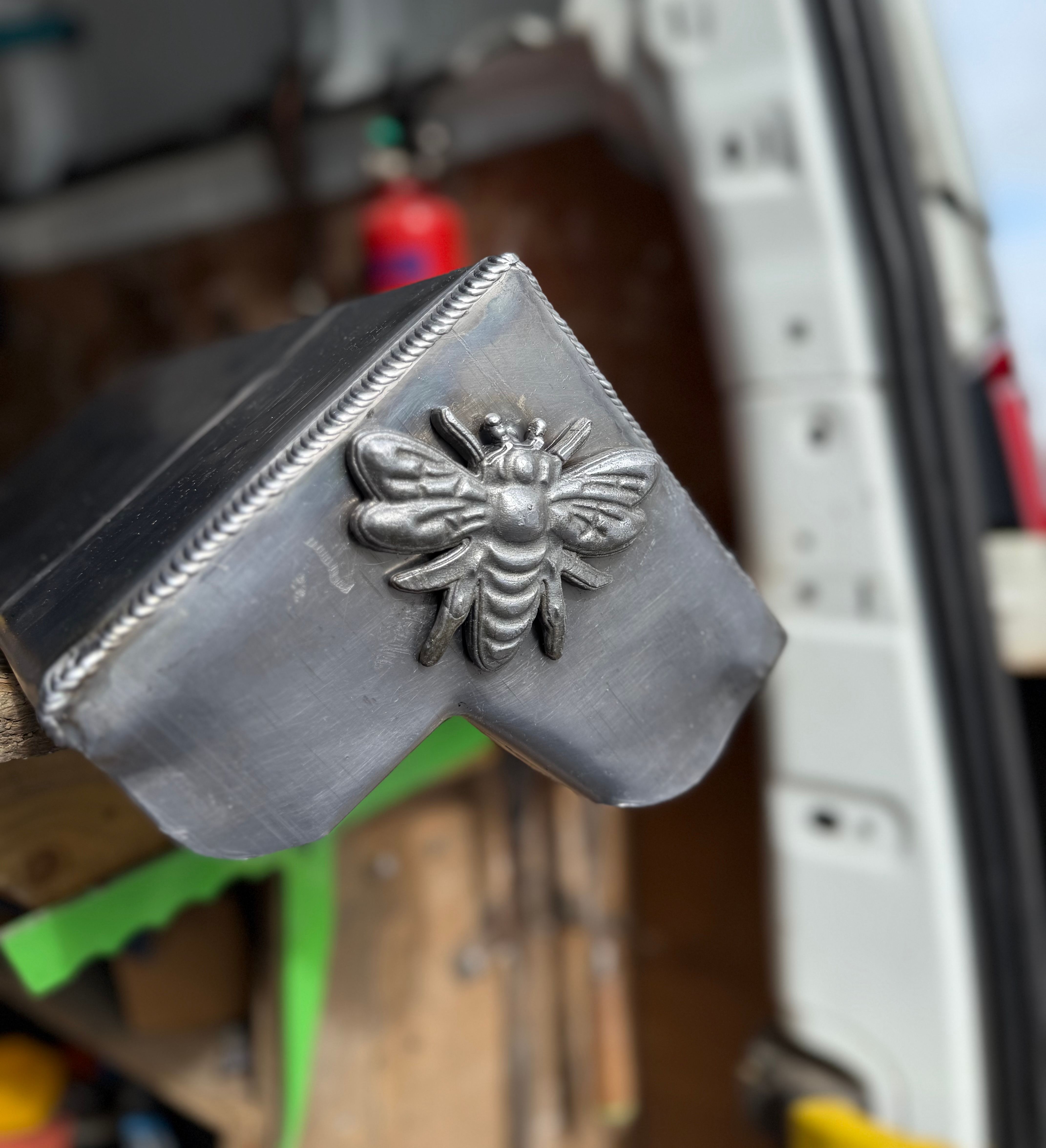 Close-up of a metal corner piece with a bee ornament attached.