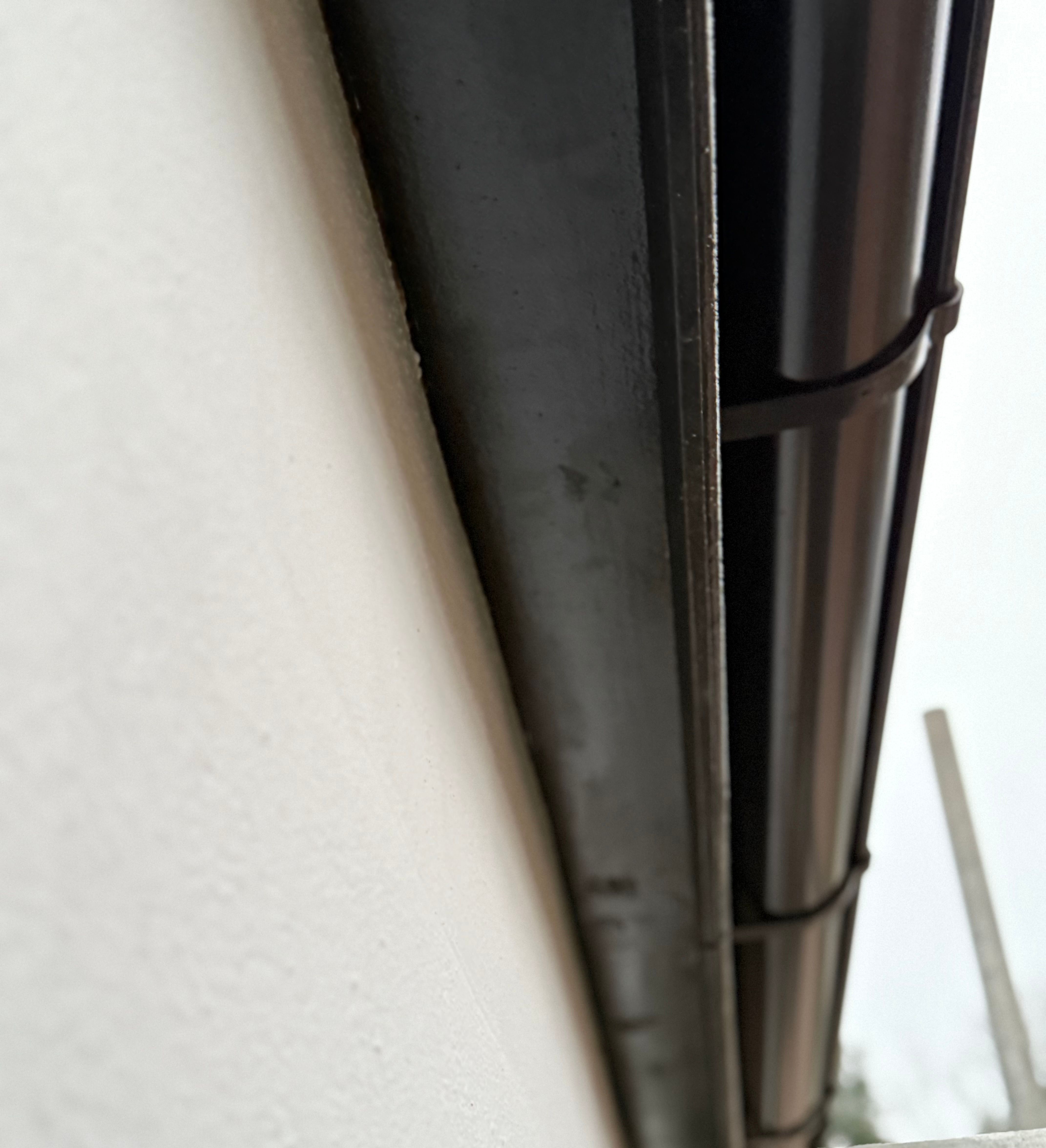 Close-up view of a metal gutter attached to the side of a building.