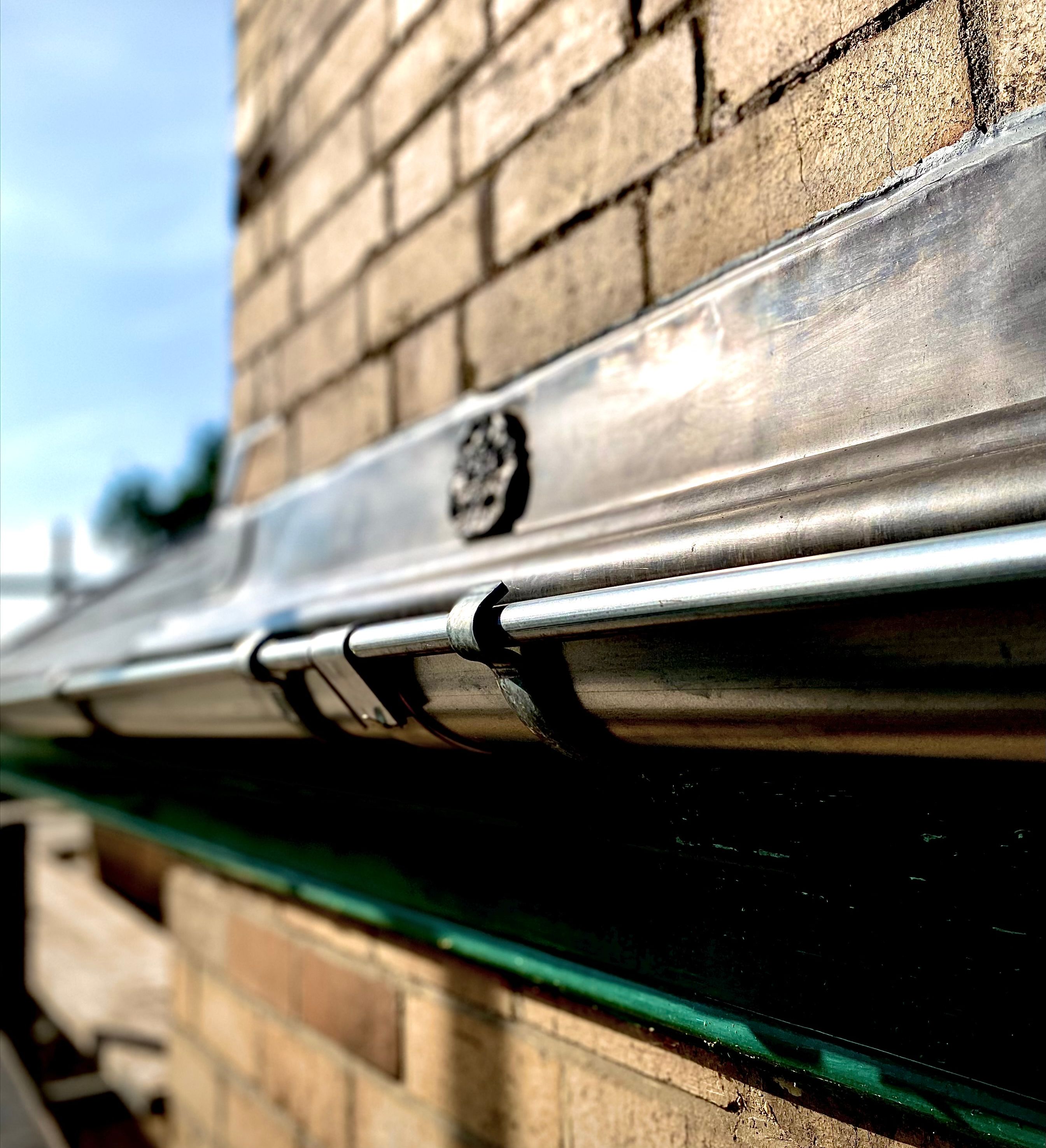 Close-up of a metal gutter attached to a brick wall