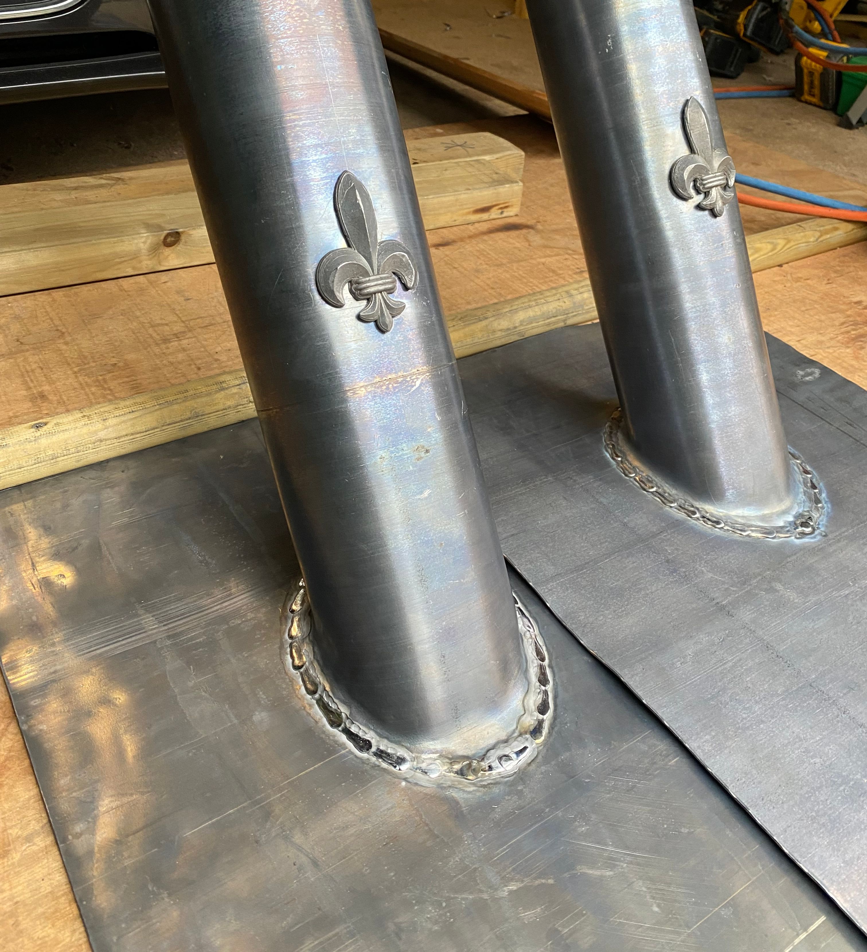 Close-up of welded metal pipes with fleur-de-lis designs in a workshop.
