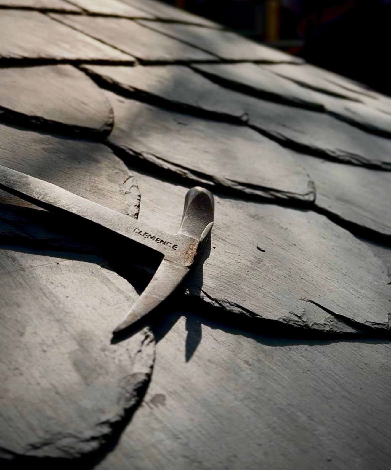 Slate roof with a slater's hammer resting on the shingles