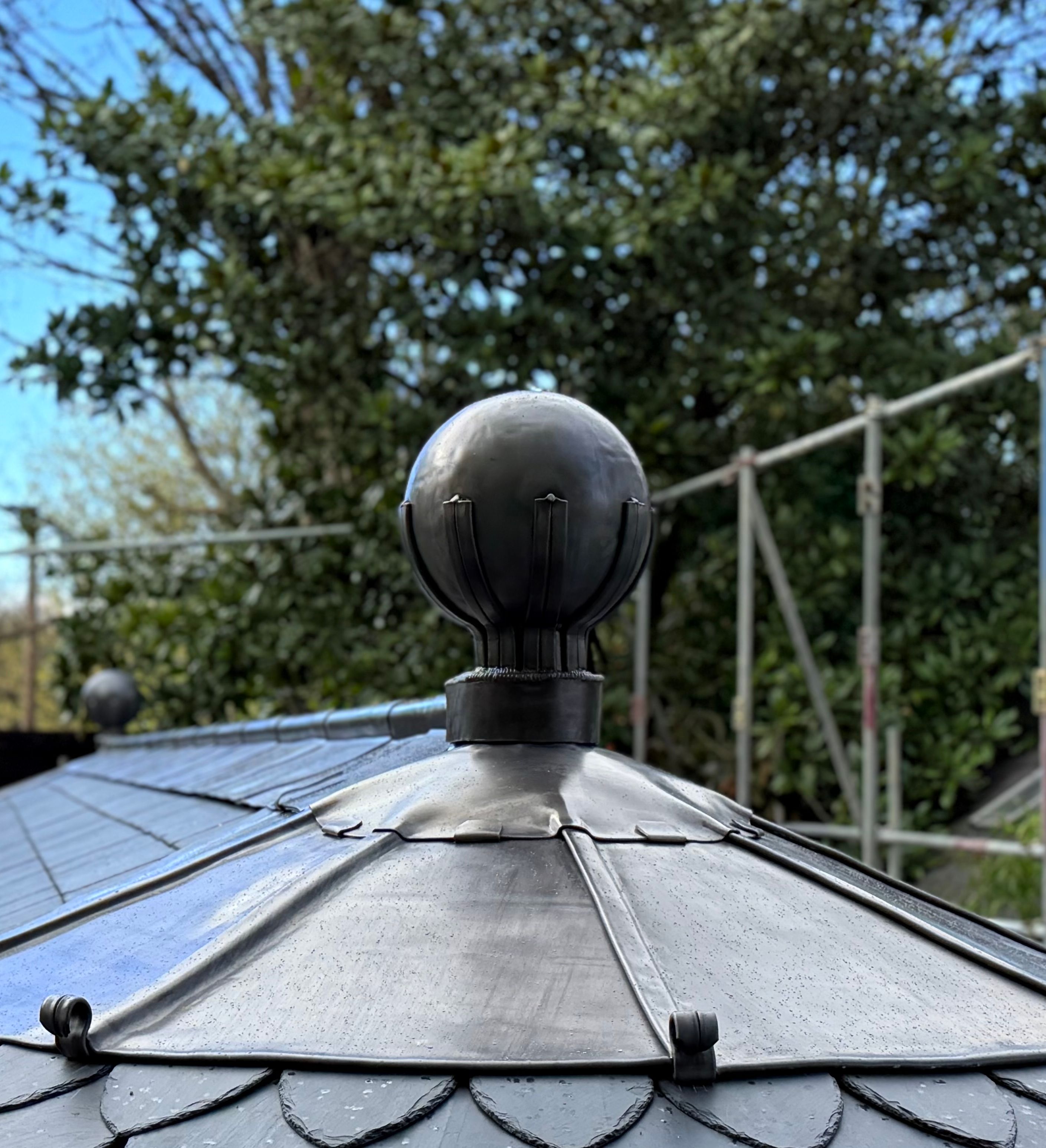 Close-up of a decorative metal finial on a shingled rooftop outdoors