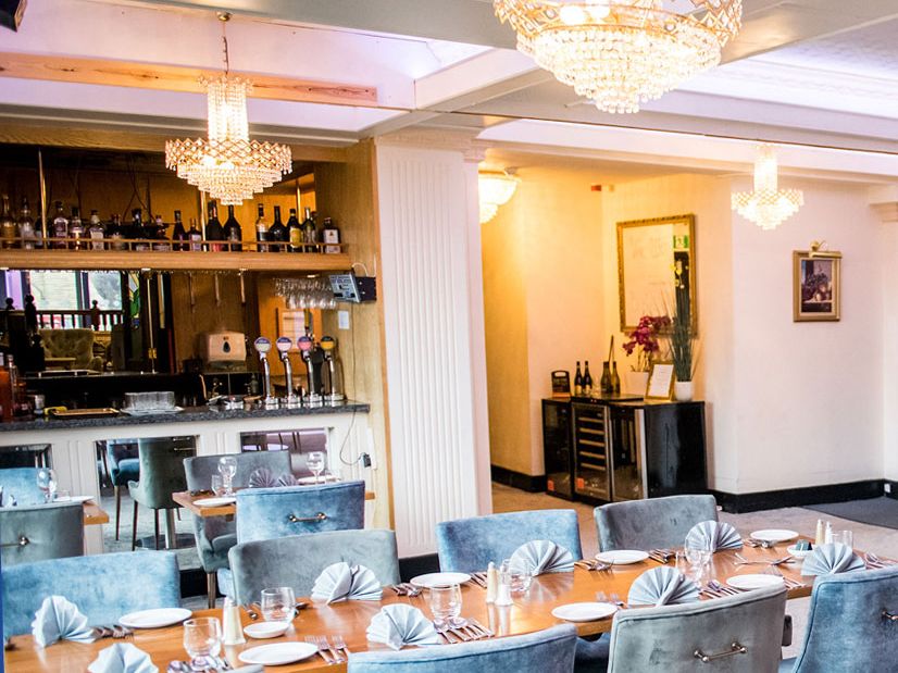 Elegant hotel restaurant dining room with chandelier lighting and bar area