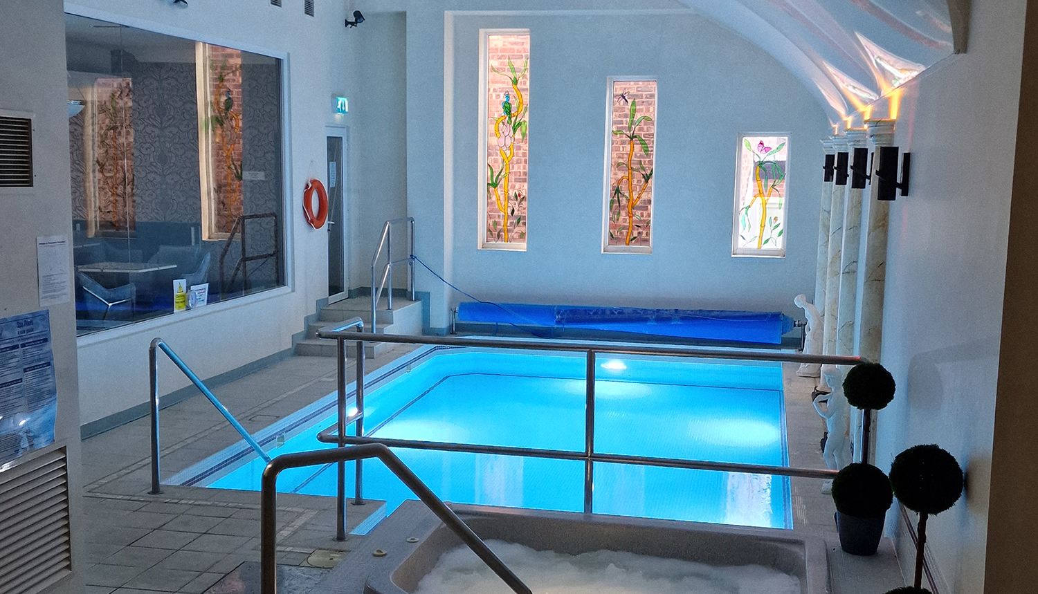 Indoor swimming pool with a small bubbling hot tub and handrails