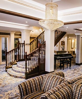 Elegant hotel lounge with patterned sofas, crystal chandeliers and a sweeping staircase