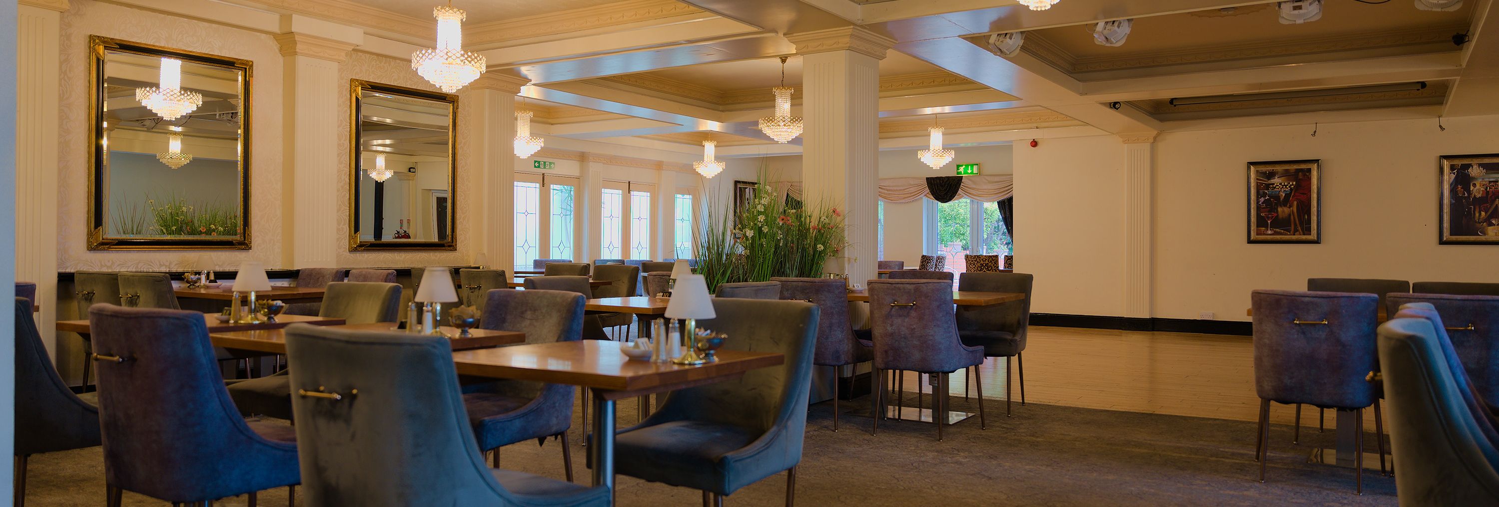 Elegant restaurant dining room with blue velvet chairs, wooden tables and crystal chandeliers