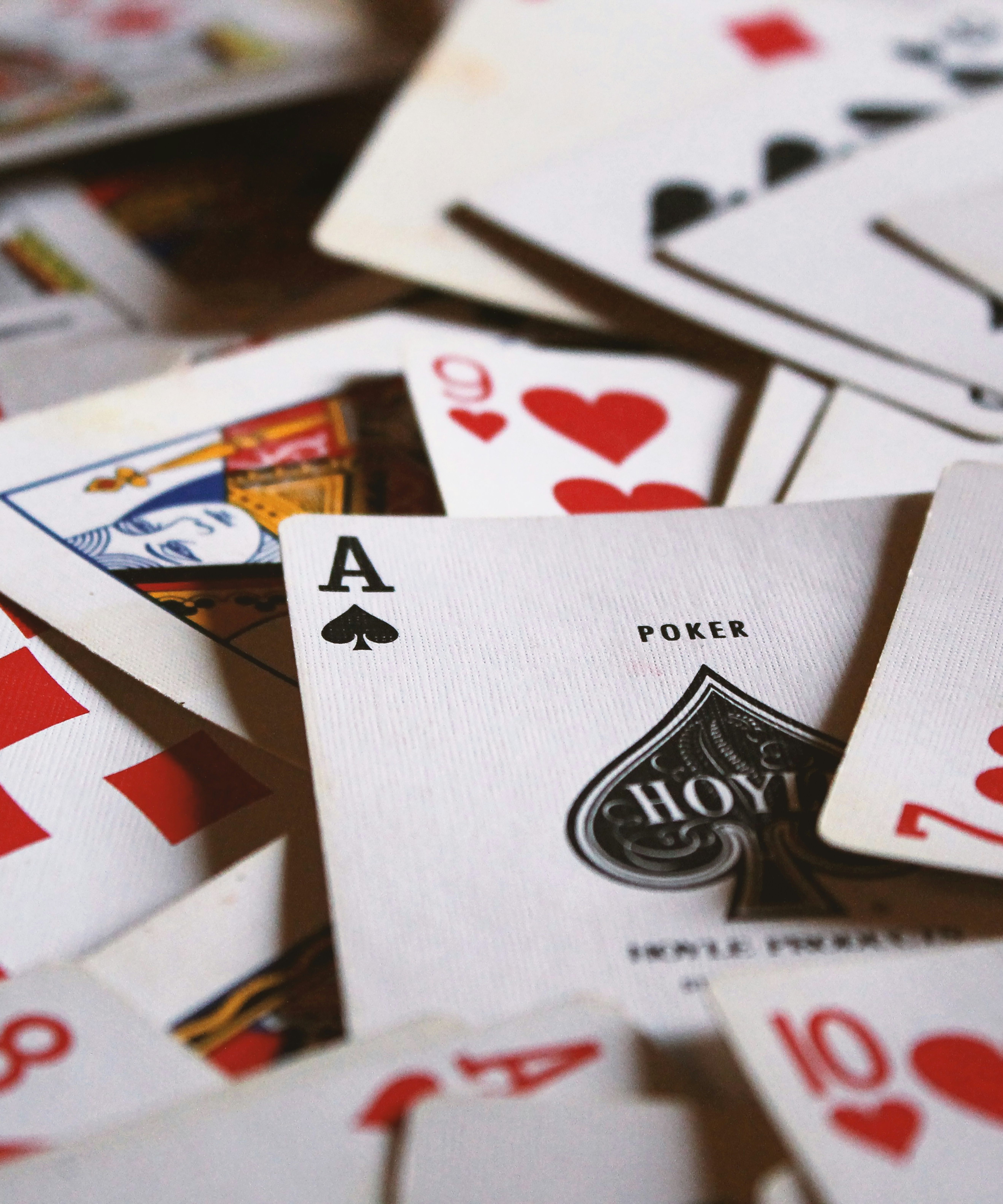 Close-up of scattered playing cards showing hearts, diamonds and the ace of spades