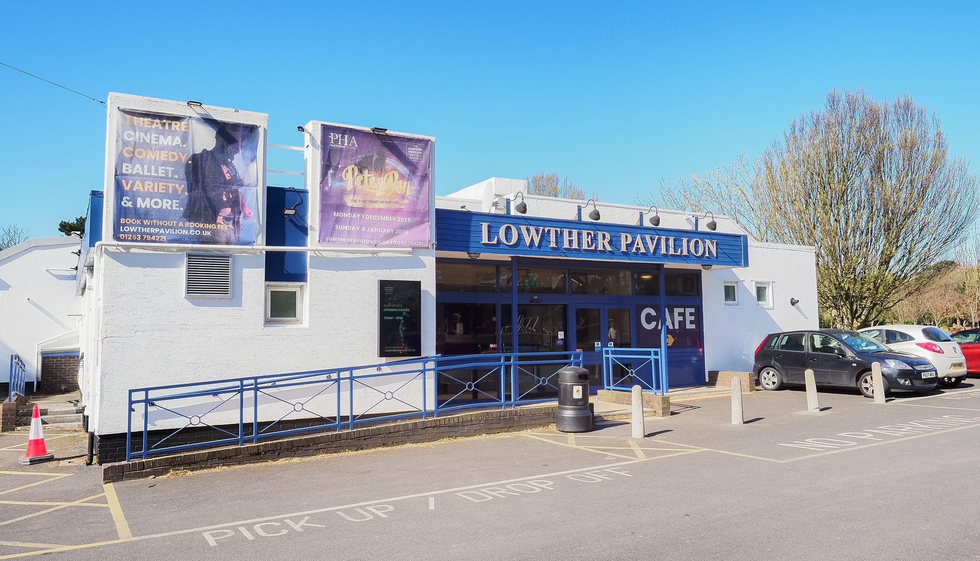 Exterior of Lowther Pavilion with café entrance and event posters under a clear blue sky
