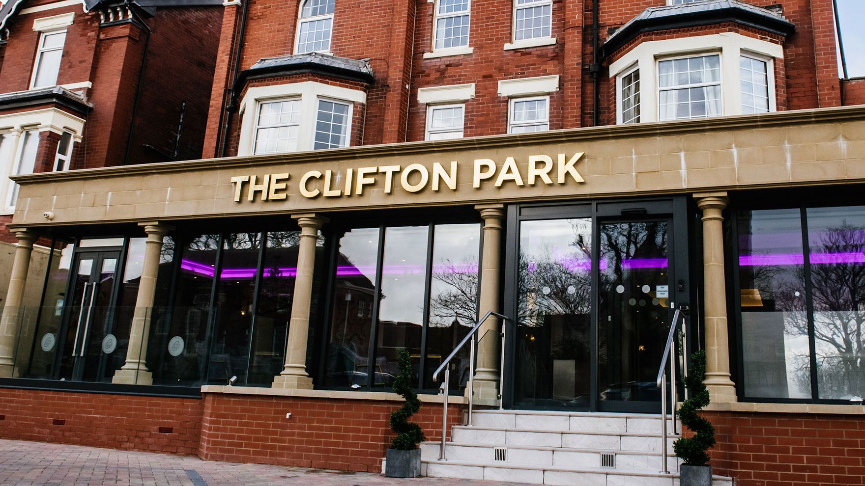 Entrance of The Clifton Park building with gold signage above glass doors