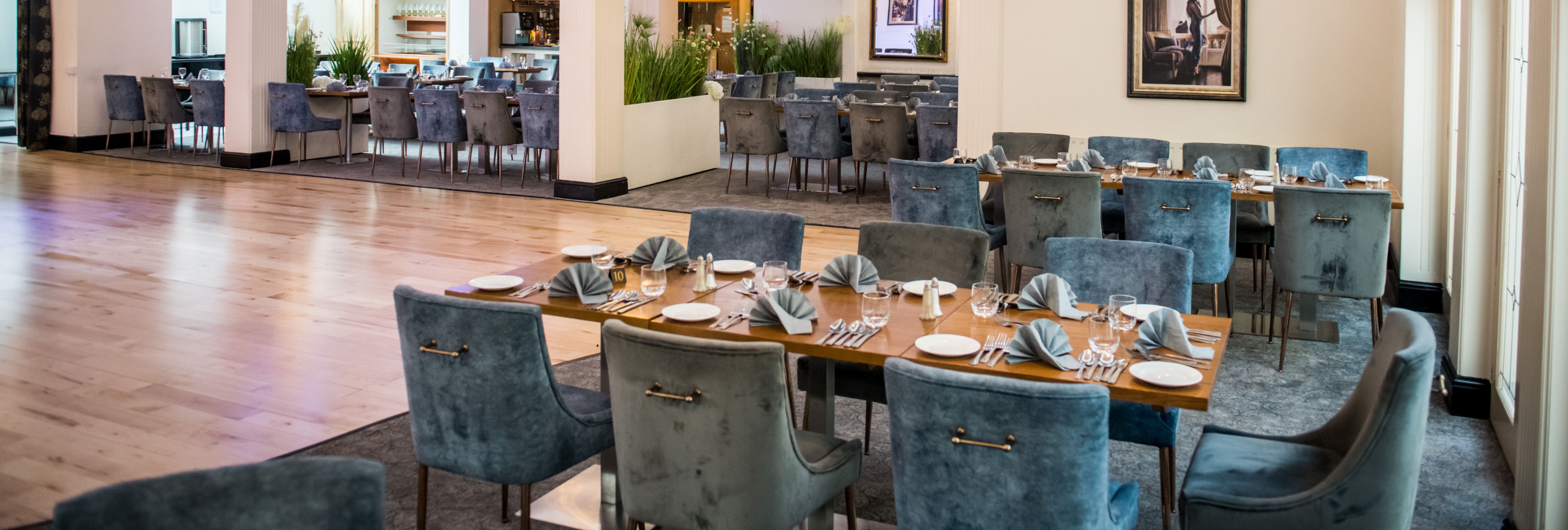 Elegant restaurant dining room with crystal chandeliers and blue velvet chairs set for a meal