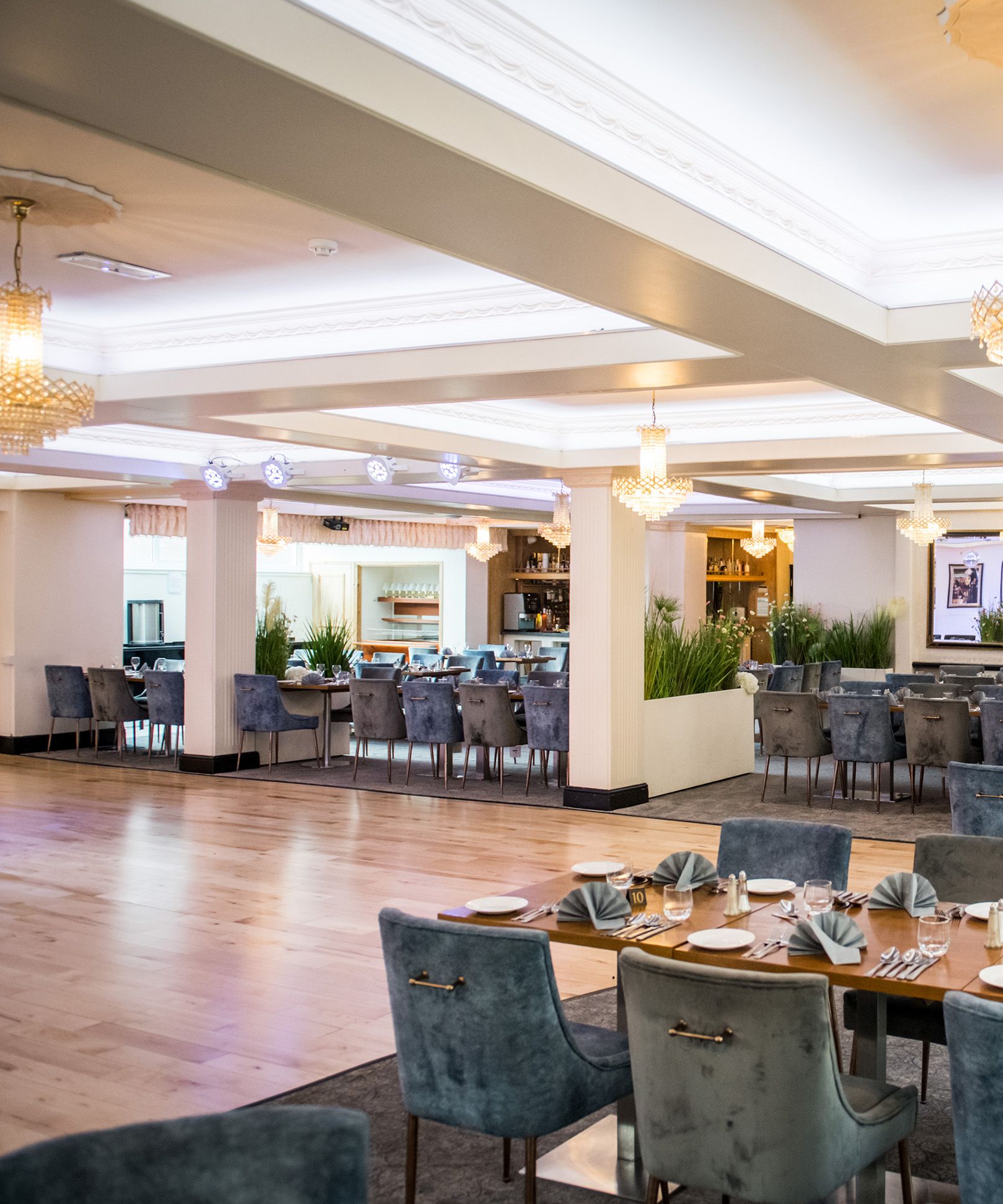 Elegant restaurant dining room with chandeliers and blue upholstered chairs