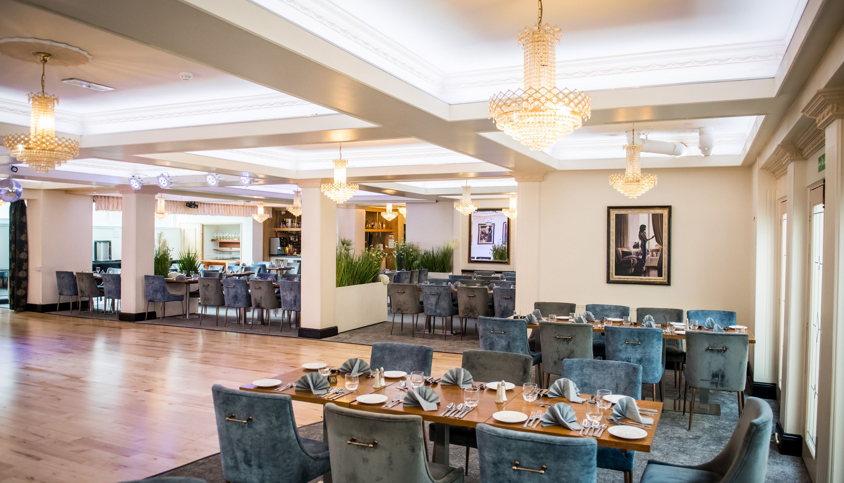 Elegant restaurant dining room with chandeliers and blue upholstered chairs