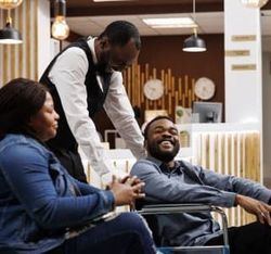 Four people interacting cheerfully in a modern indoor setting, with one person seated in a wheelchair.