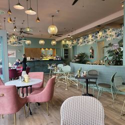 Bright, modern café interior with pastel furniture and decorative lighting.