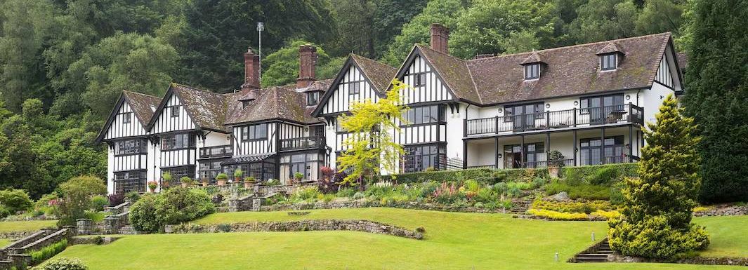 Large Tudor-style country house with manicured lawns and gardens