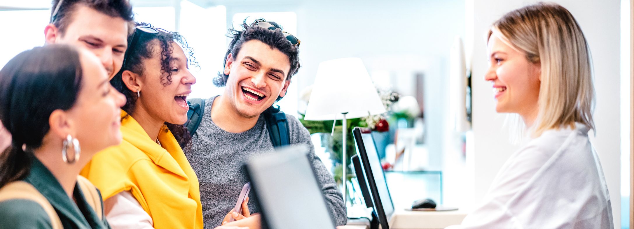 Group of young friends checking in at a hotel reception with a smiling receptionist