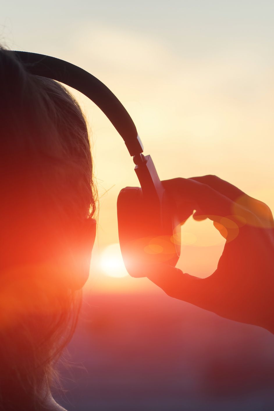 Person listening to headphones at sunset