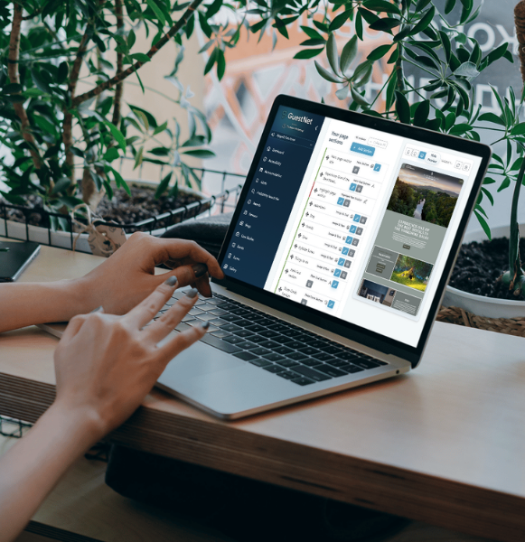 Person using a laptop displaying the GuestNet dashboard interface at a desk surrounded by plants.