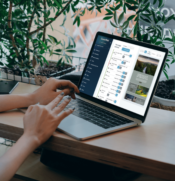 Person using a laptop displaying the GuestNet dashboard interface at a desk surrounded by plants.