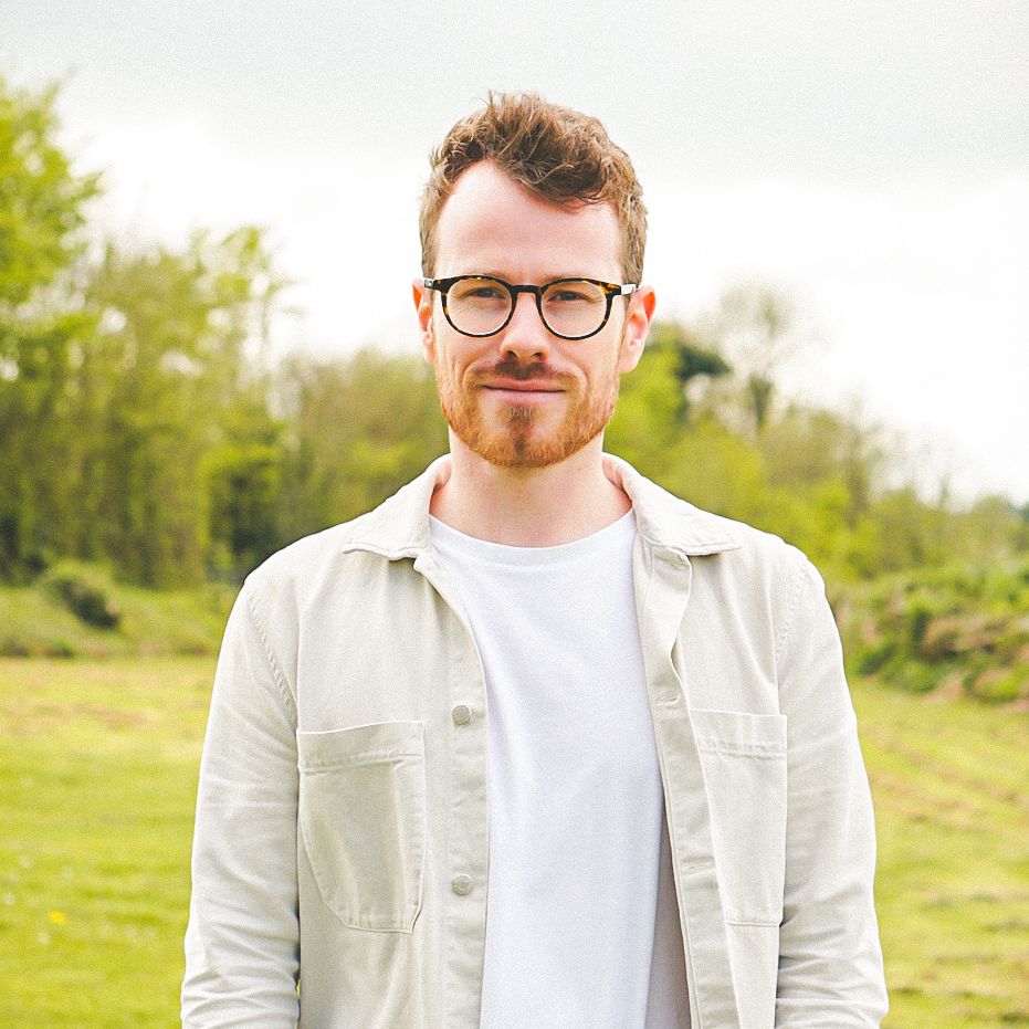 Man with glasses standing outdoors in a field