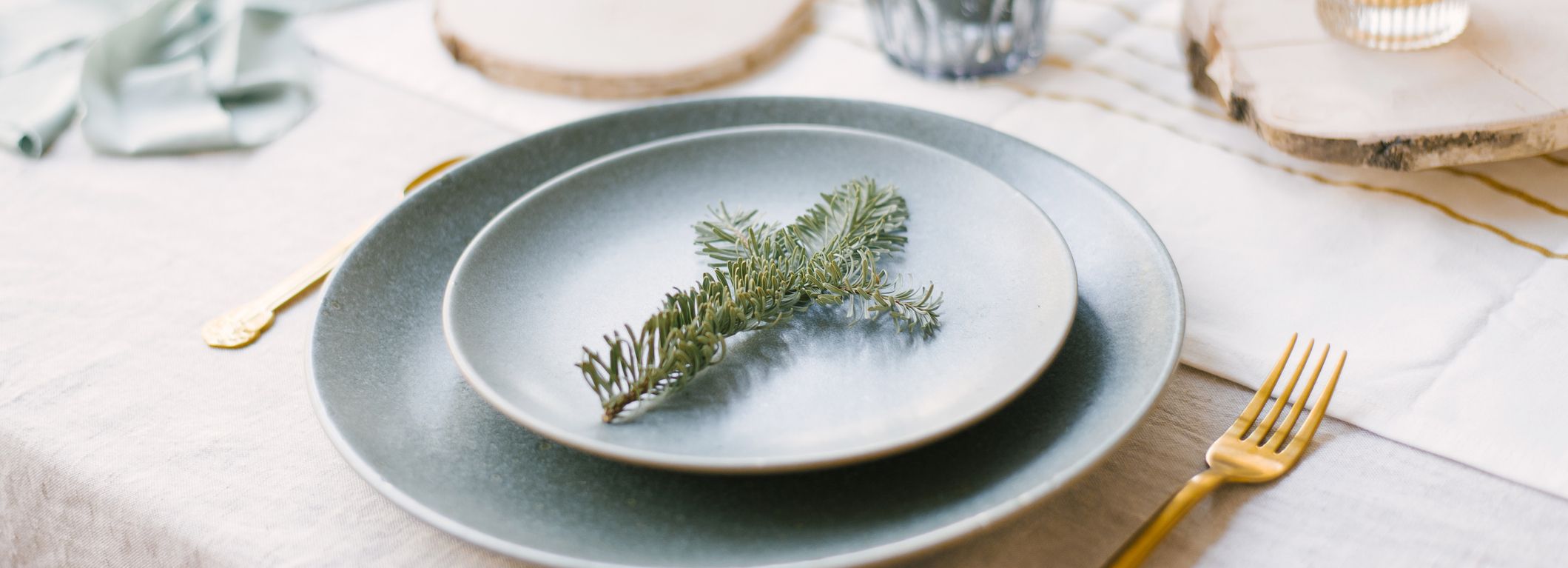 Elegant holiday table setting with pine branch on plate