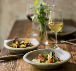 Dinner and wine on table with bunch of wildflowers