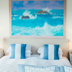 Bed with blue stripe cushions and coastal painting