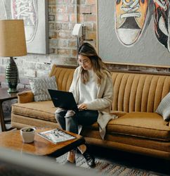 Woman sat on sofa working on laptop