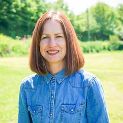 Woman standing outdoors wearing a denim shirt and light-colored pants